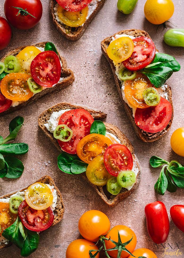Colorful bruschetta topped with fresh tomatoes and basil leaves on a rustic surface.
