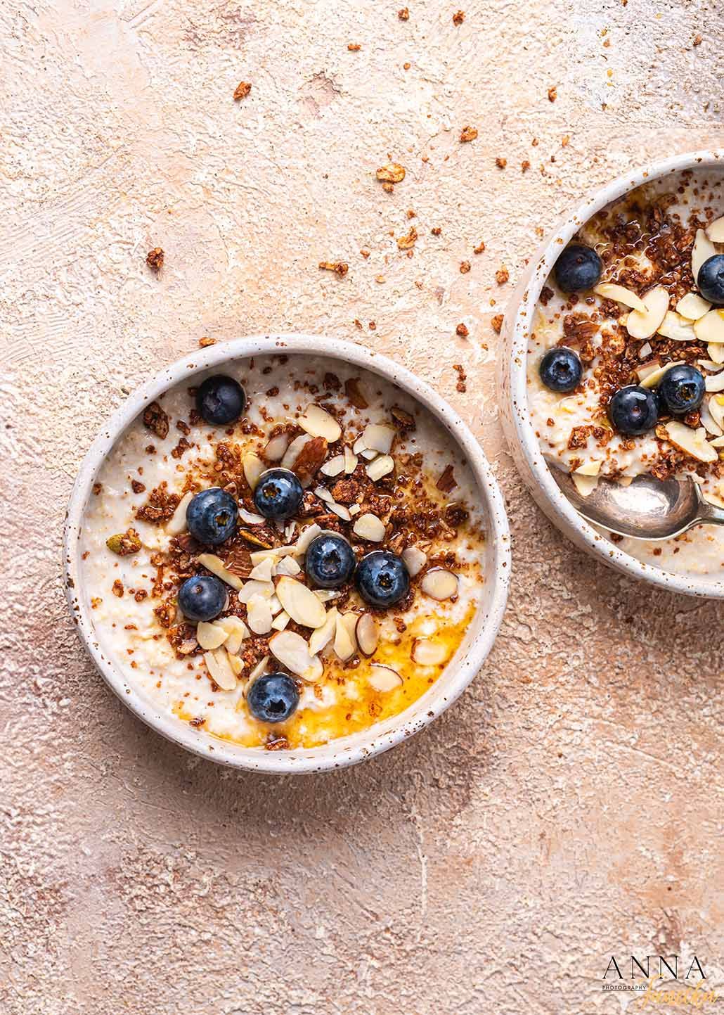 Progression of a breakfast bowl with yogurt, blueberries, and granola being assembled.