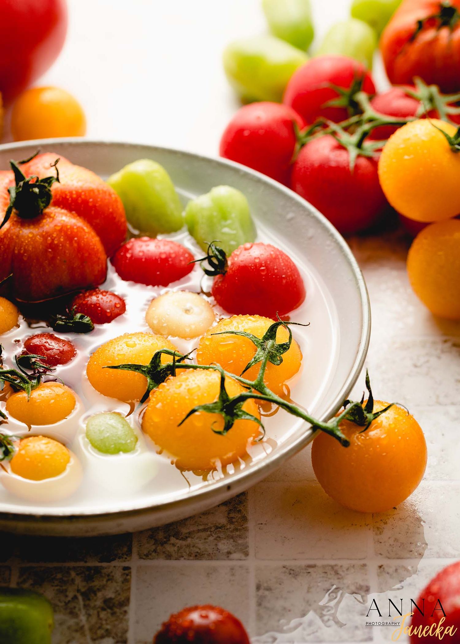 Colorful assortment of fresh tomatoes displayed on a white plate with green garnish.