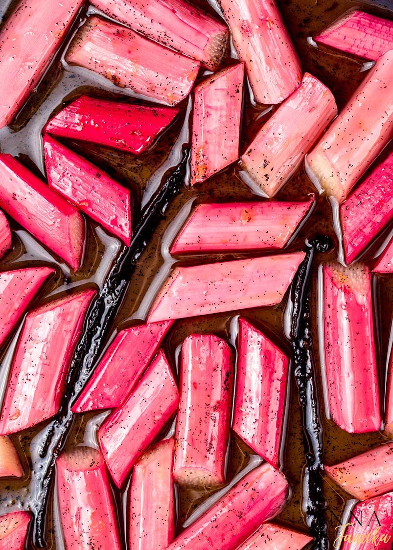 Sliced pink rhubarb stalks arranged in rows on a dark surface creating a vibrant pattern.