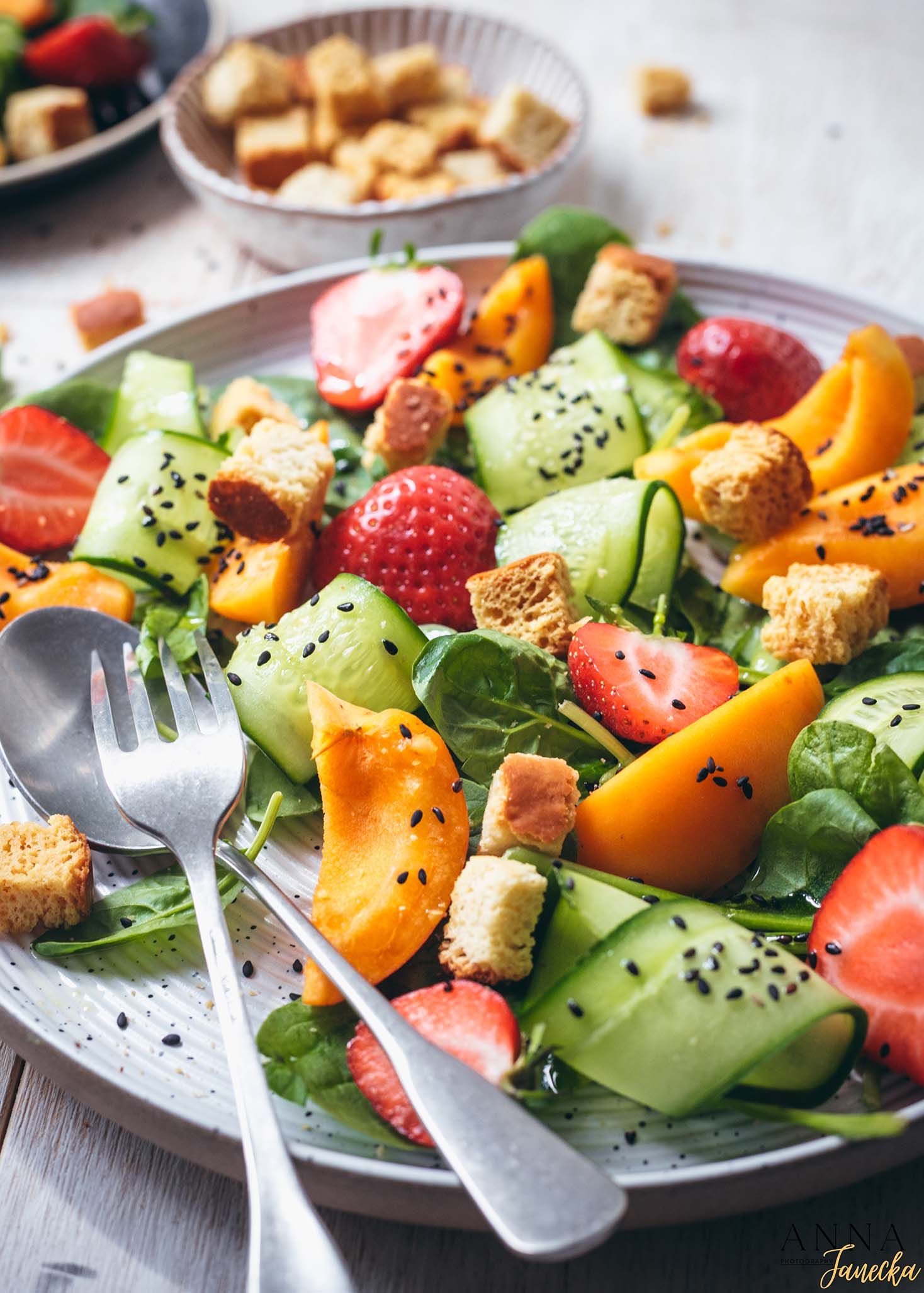 Fresh summer salad with strawberries, cucumbers, croutons and black sesame seeds.