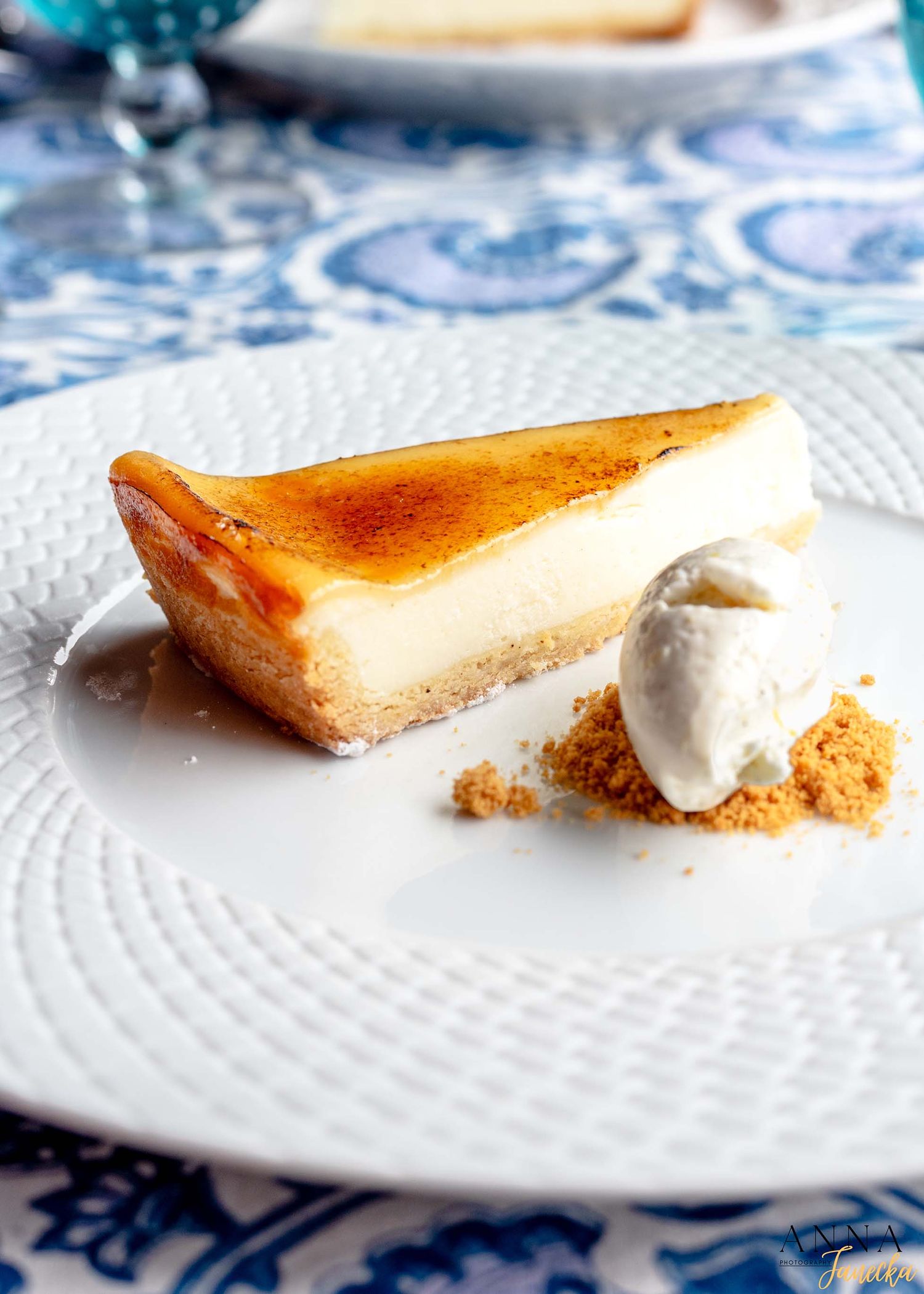 Slices of creamy cheesecake with whipped cream on white textured plates.
