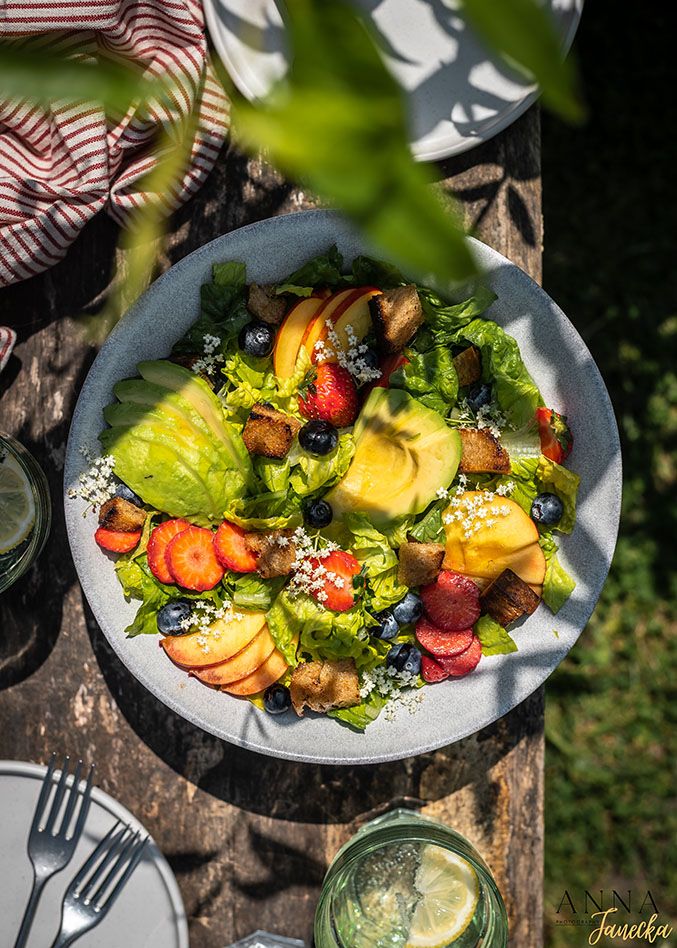 Fresh garden salad with avocado and vegetables served on a white plate outdoors.