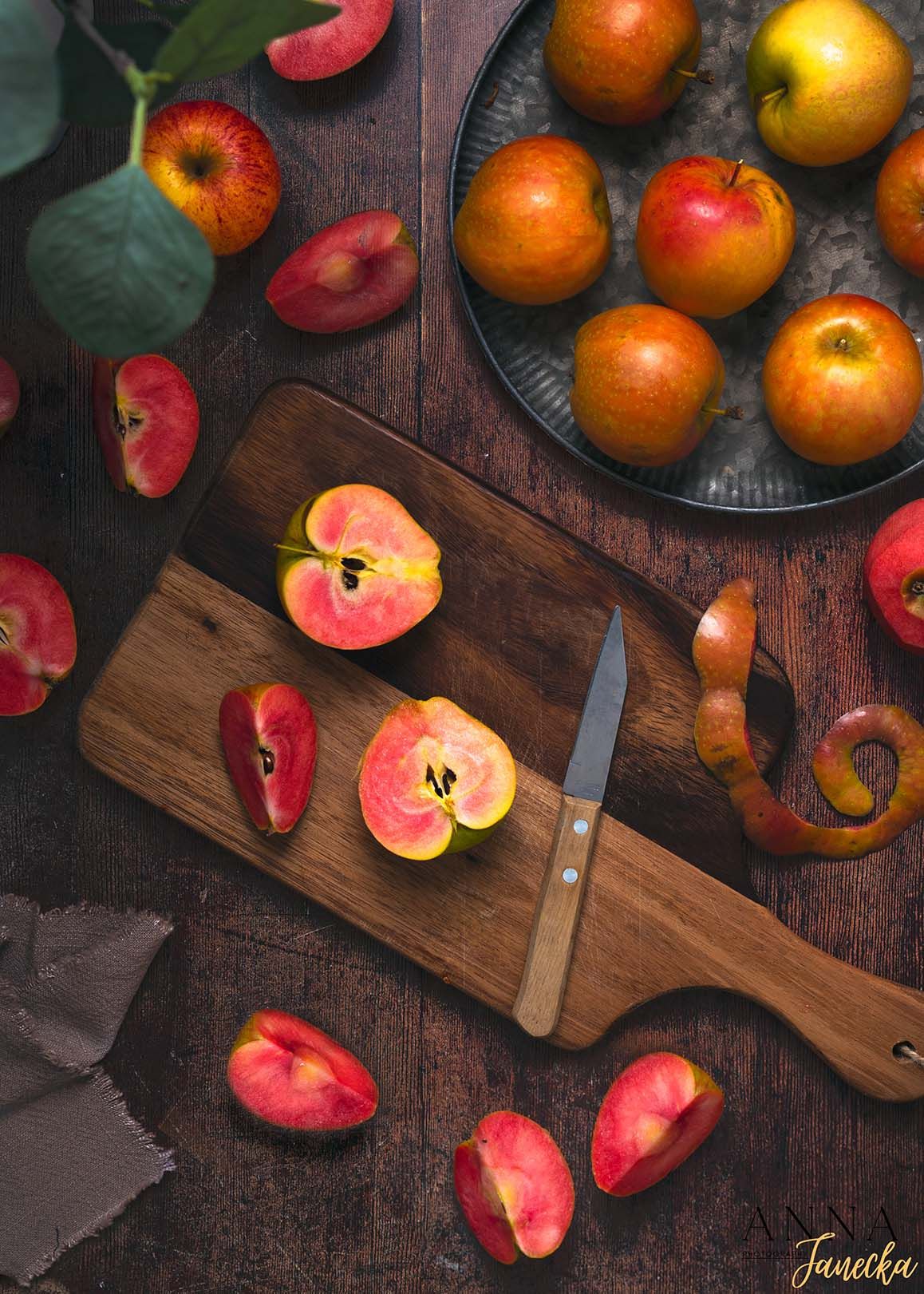 Fresh red and yellow apples arranged on a wooden cutting board with scattered slices.