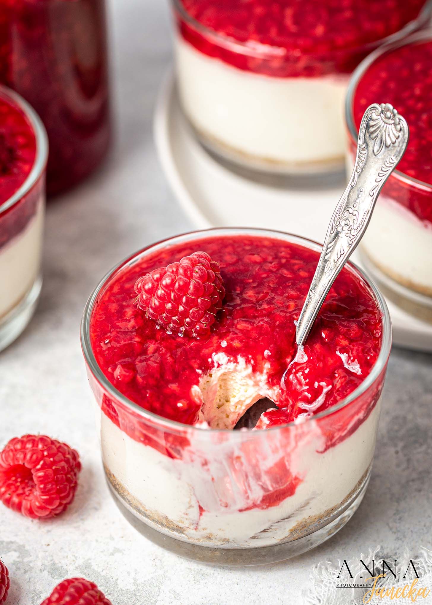 Creamy dessert topped with fresh red raspberries served in glass bowls.