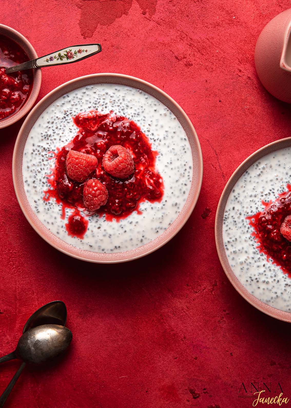 White chia pudding with red berry topping served on vibrant red background.