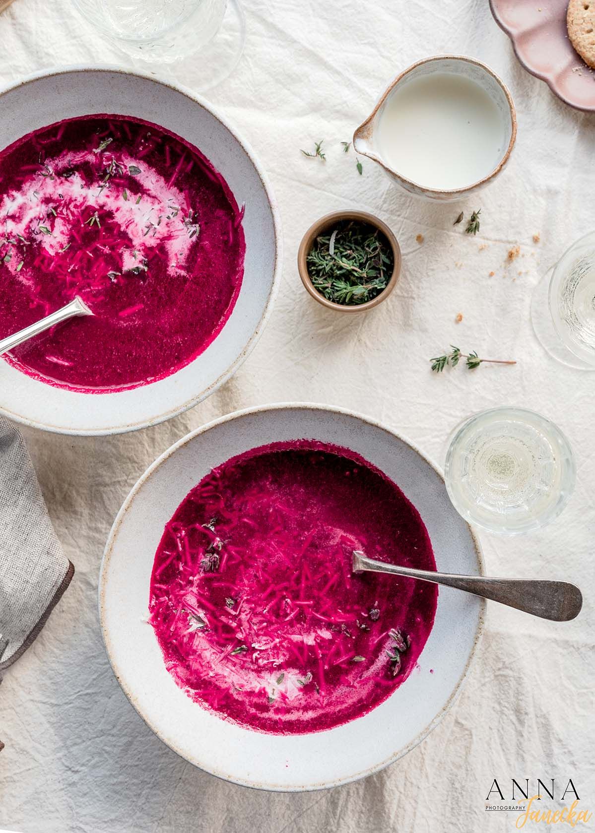 Vibrant beetroot soup served in white bowls on a light textured background.