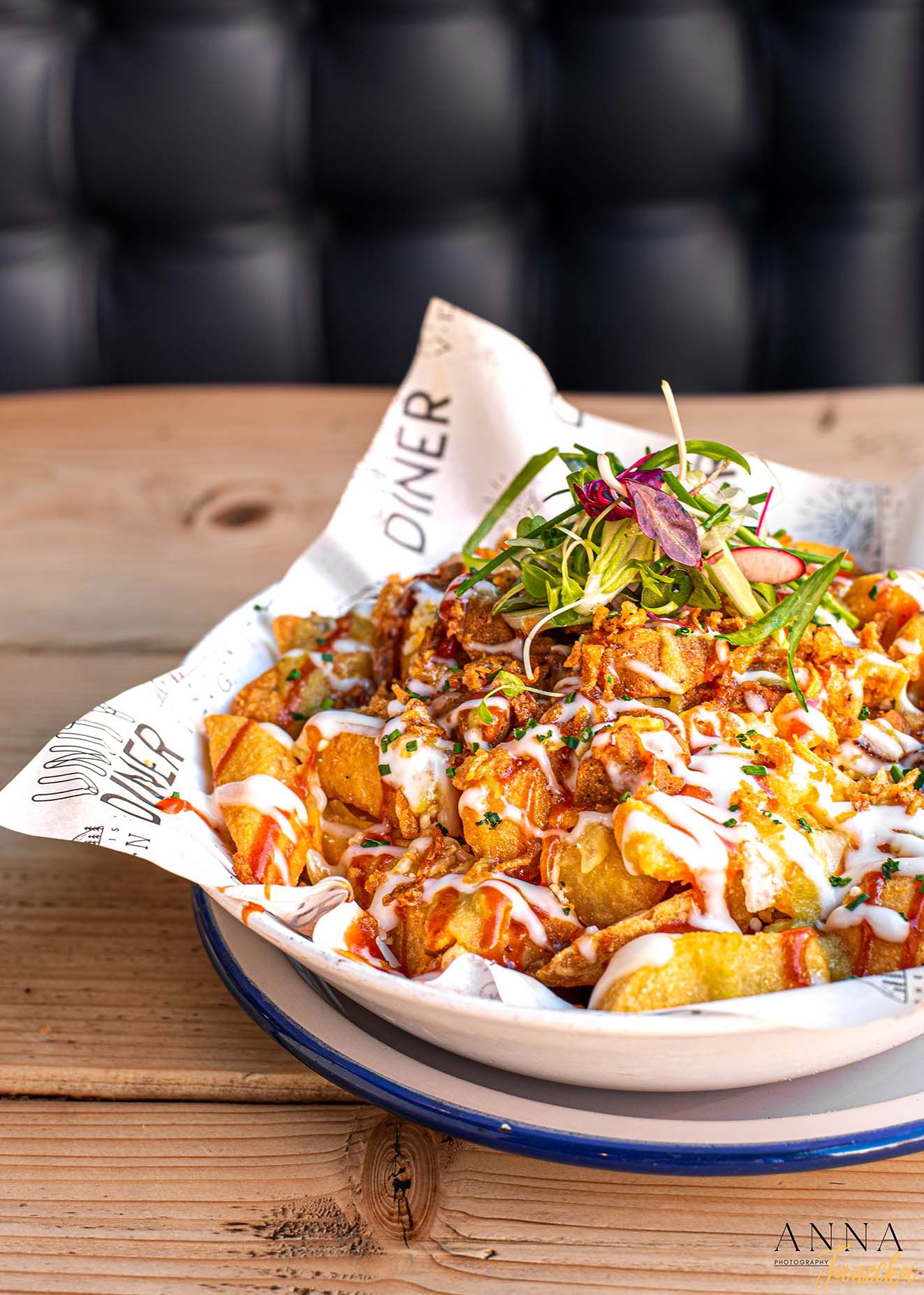 Loaded potato wedges topped with sauce, meat, and microgreens in a restaurant dish.