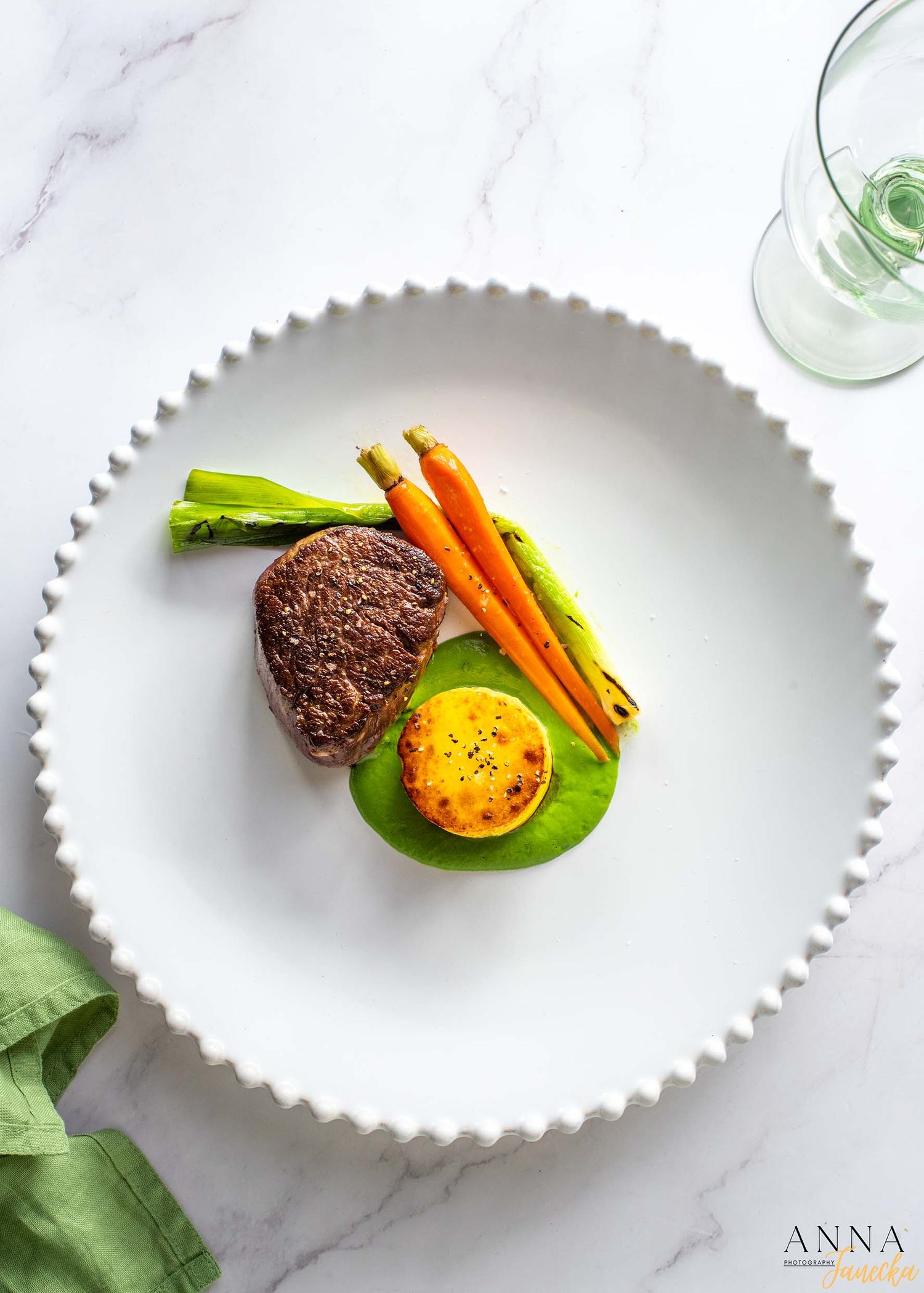 Plated presentation of vegetables and meatballs on white scalloped dishes.