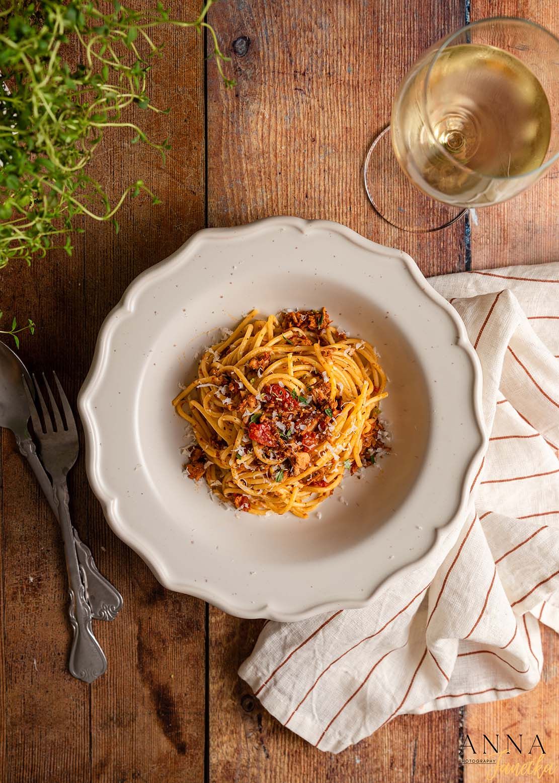 Pasta dish with meat sauce served on an elegant white plate on a rustic wooden table.