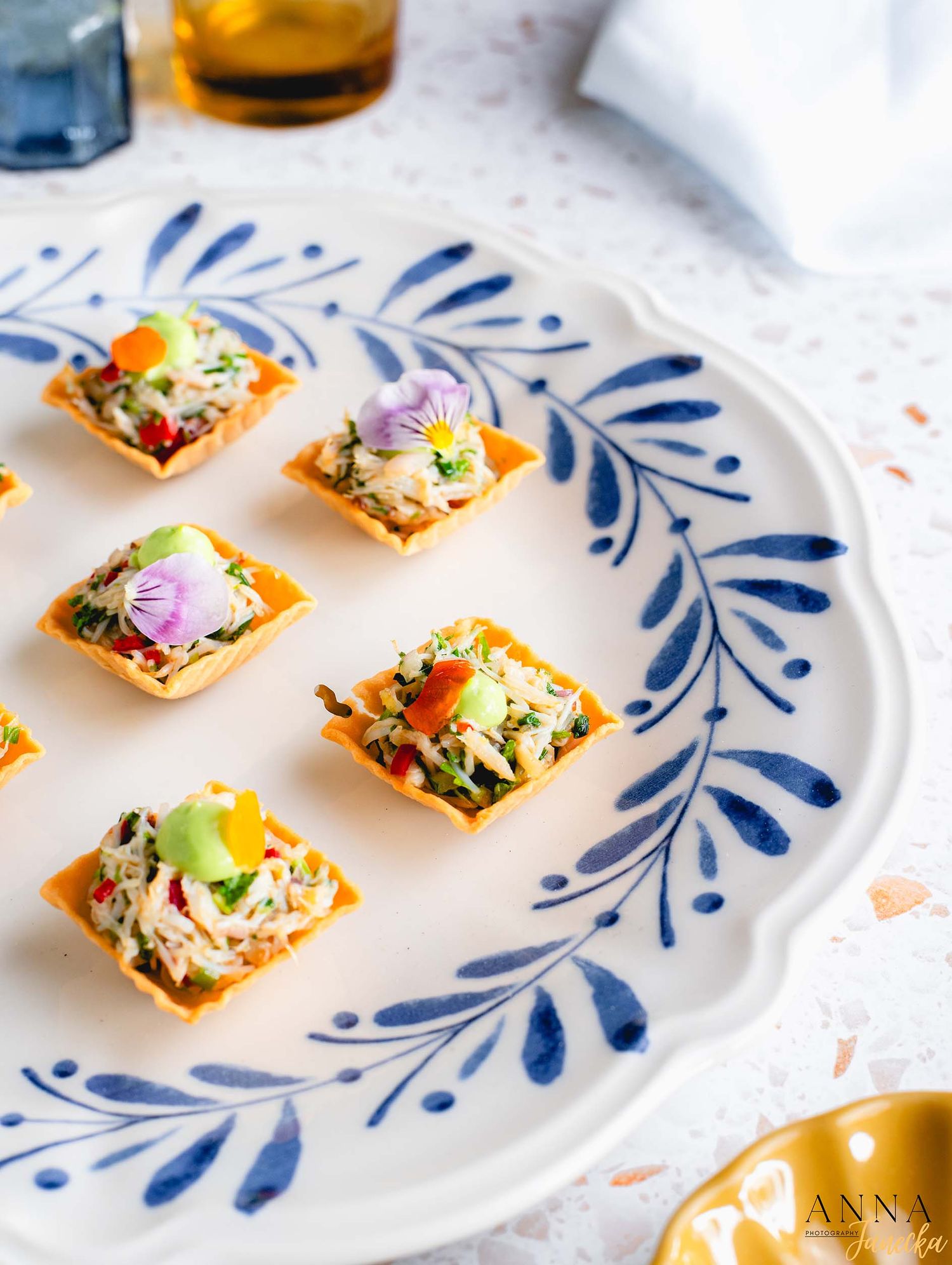 Colorful appetizer bites arranged on a blue and white decorative plate.