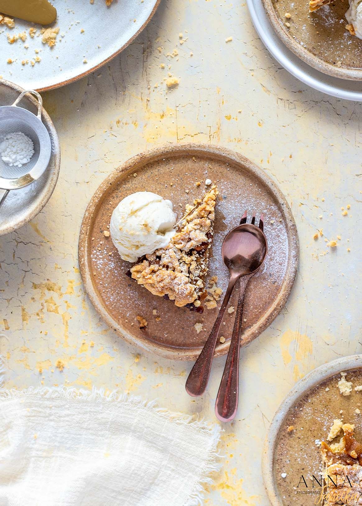 Crumbled desserts and pastries served on rustic brown plates with silverware against a light background.