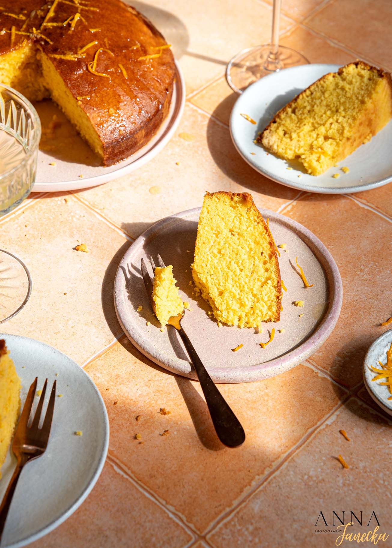 Golden orange cake slices served on gray plates with warm lighting.