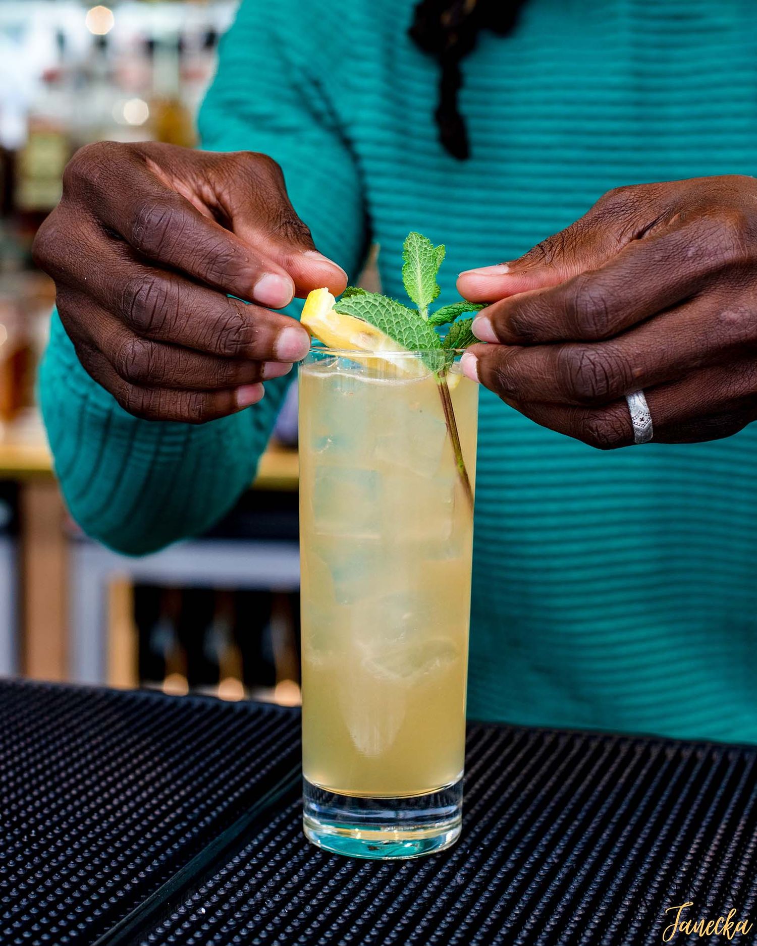 Citrus cocktails being garnished with fresh herbs at a bar.