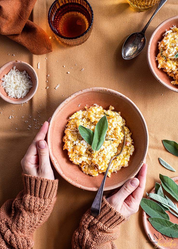 Creamy risotto served in a terracotta bowl with fresh herbs and grated parmesan.