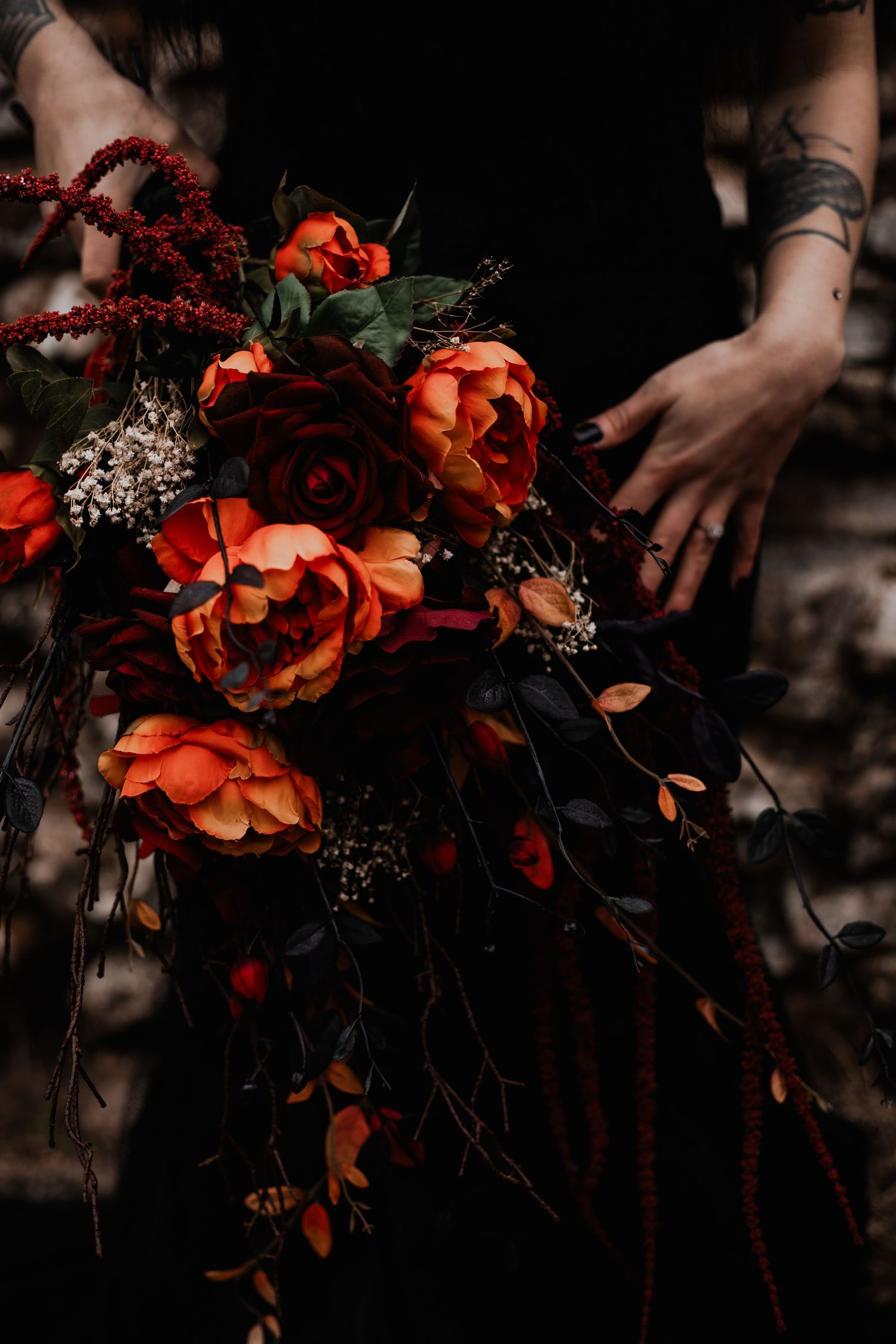 A series of darkly moody floral arrangements featuring rich orange and burgundy blooms with dramatic shadows and hands.