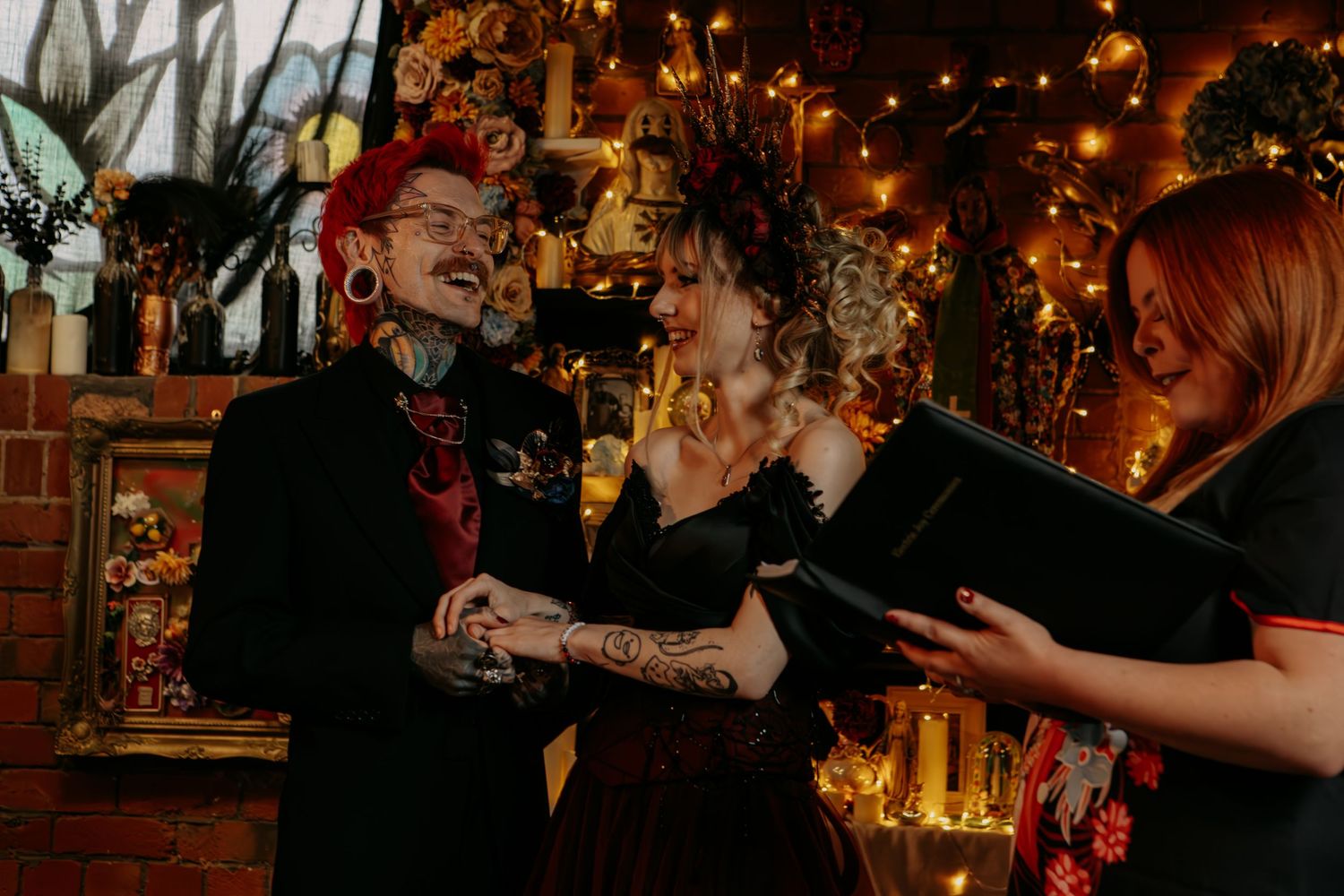Couple celebrates at intimate wedding reception with warm string lights and brick wall backdrop.