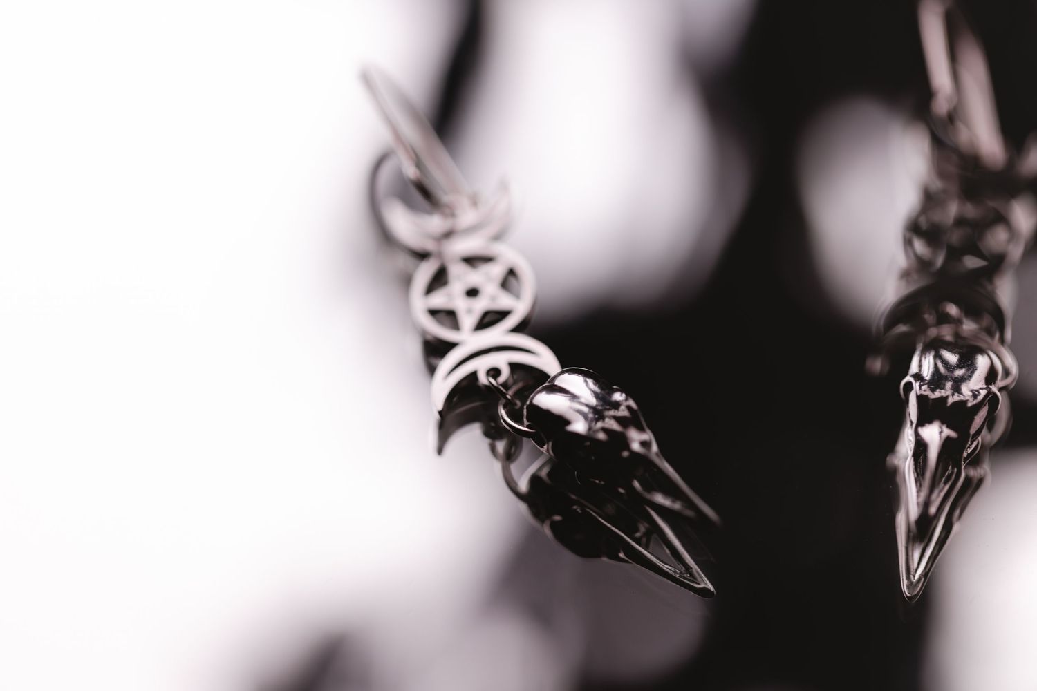 Macro shot of metallic jewelry or pendant showing sharp pointed ends in black and white with blurred background.