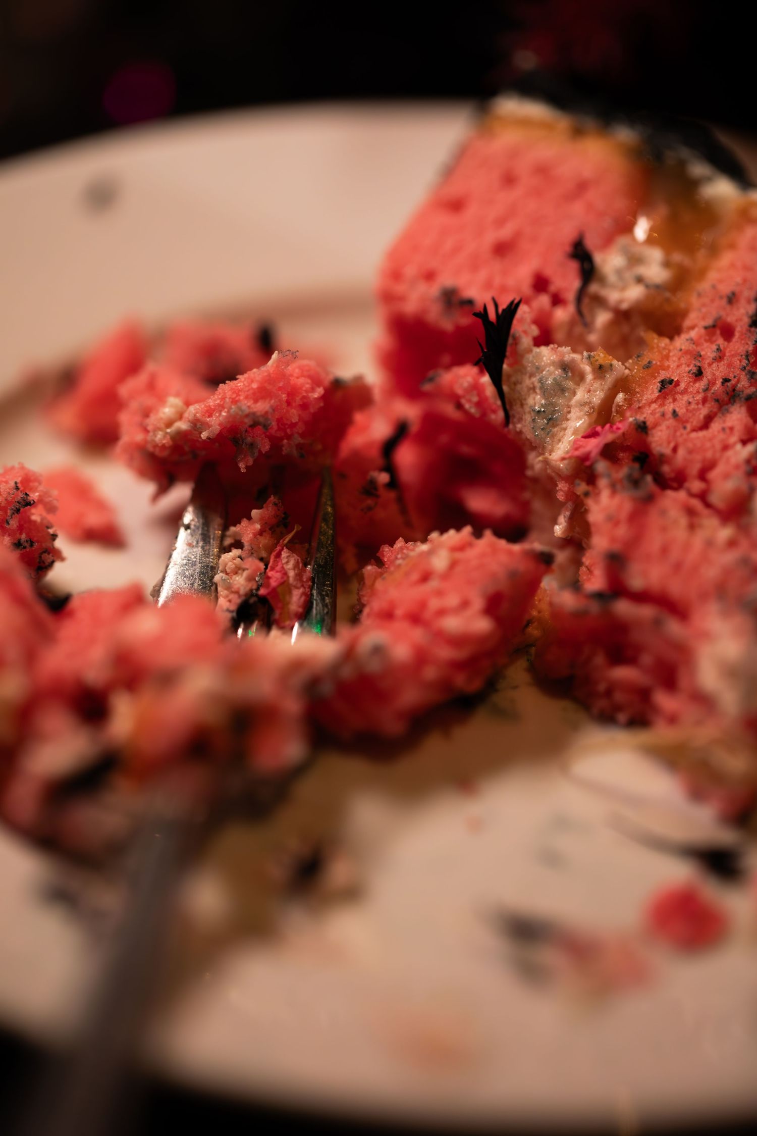 Close-up macro shot of moist red velvet cake crumbs on a white plate showing rich texture and vibrant color.