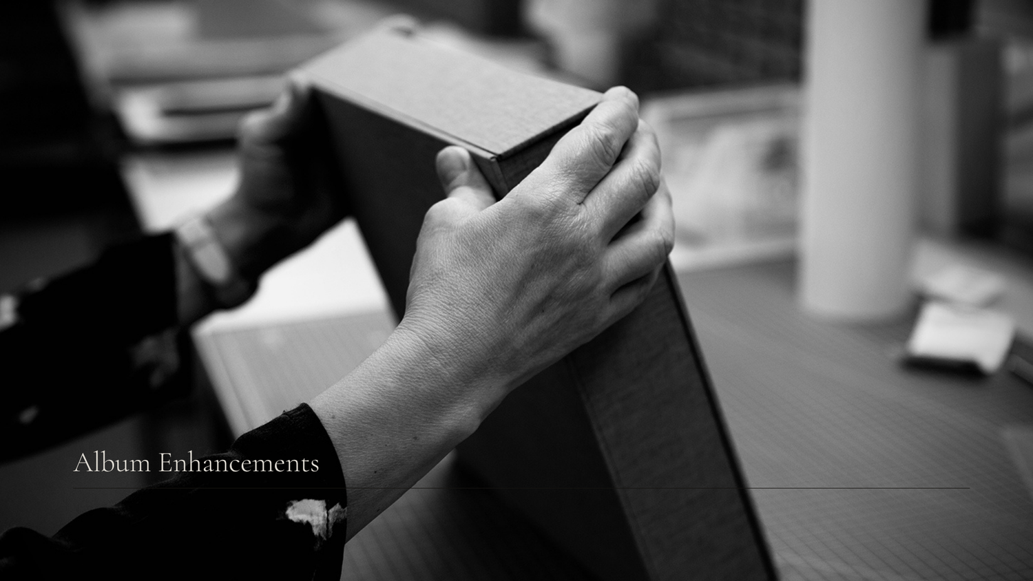 Black and white closeup of hands holding and examining an open book or notebook.