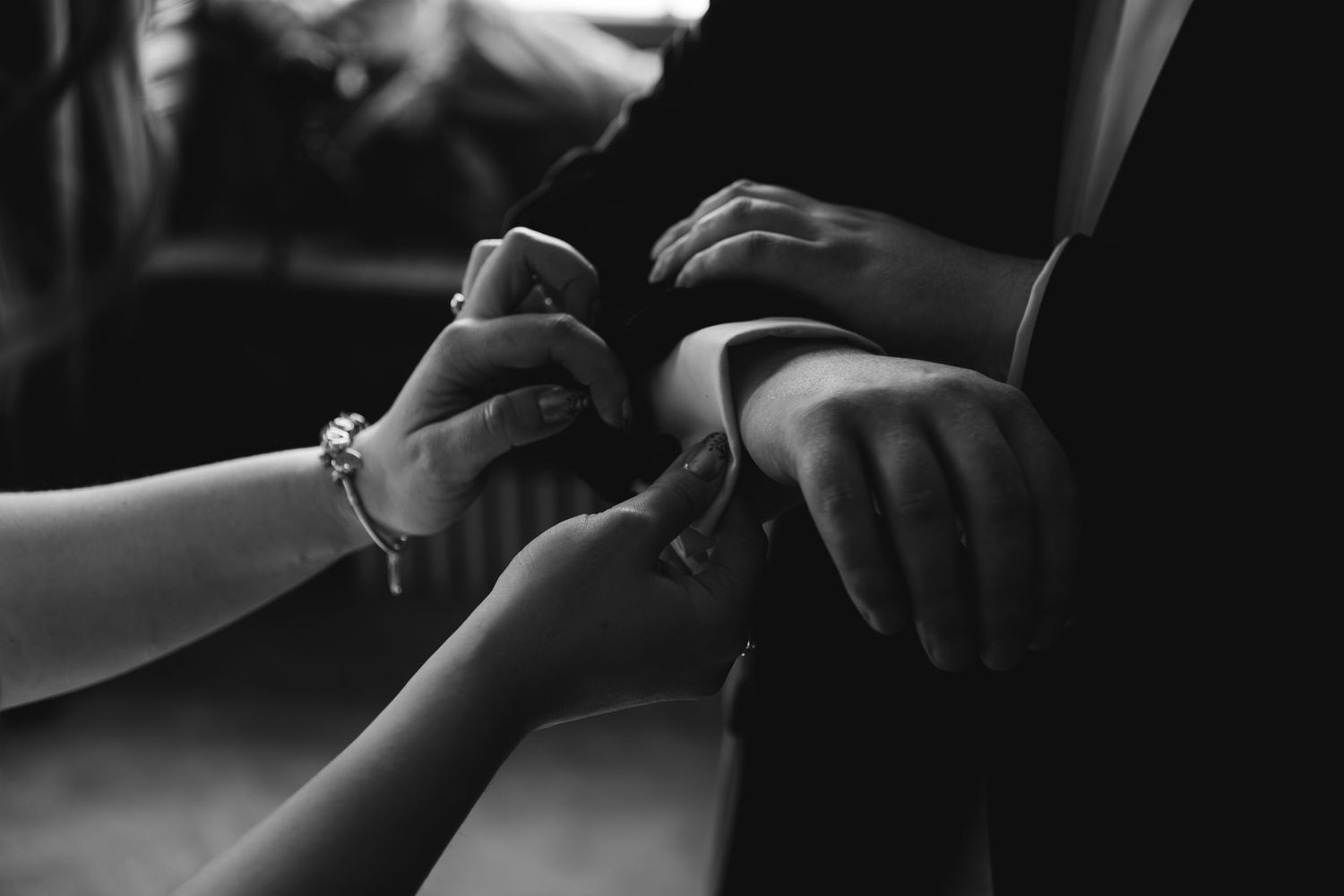 Close-up black and white photo of hands holding and comforting another person's hands in intimate moment.