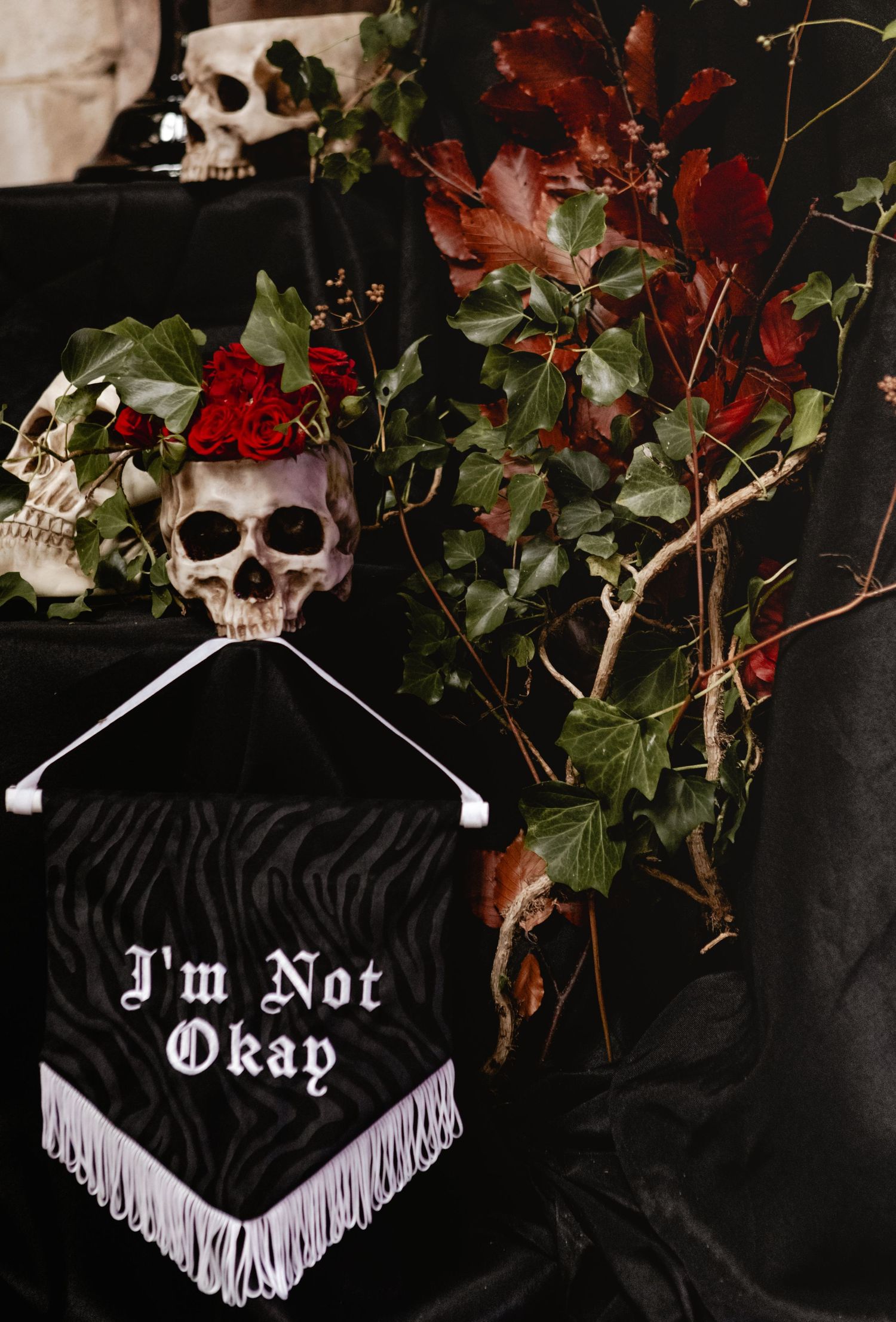 Gothic themed decorative masks with fringe adorned with red roses and foliage against a dark background.