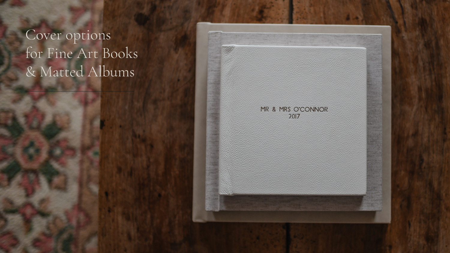 A light gray photo album or book on a textured floral surface with muted tones.