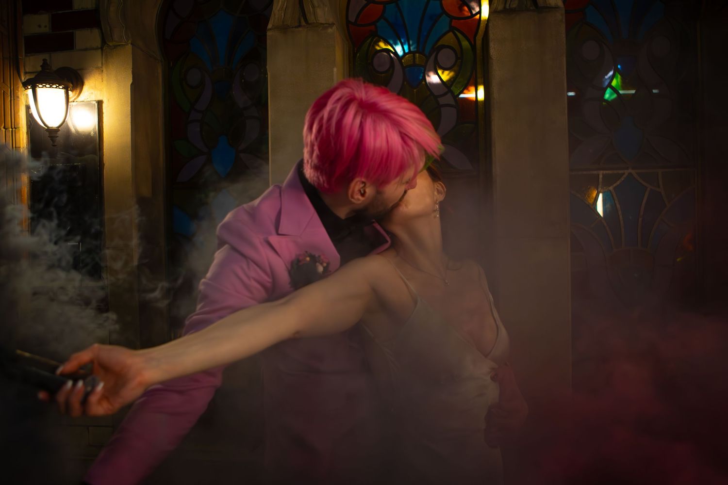 A person with pink hair dancing in a smoky, dimly lit nightclub atmosphere with colored lights in the background.