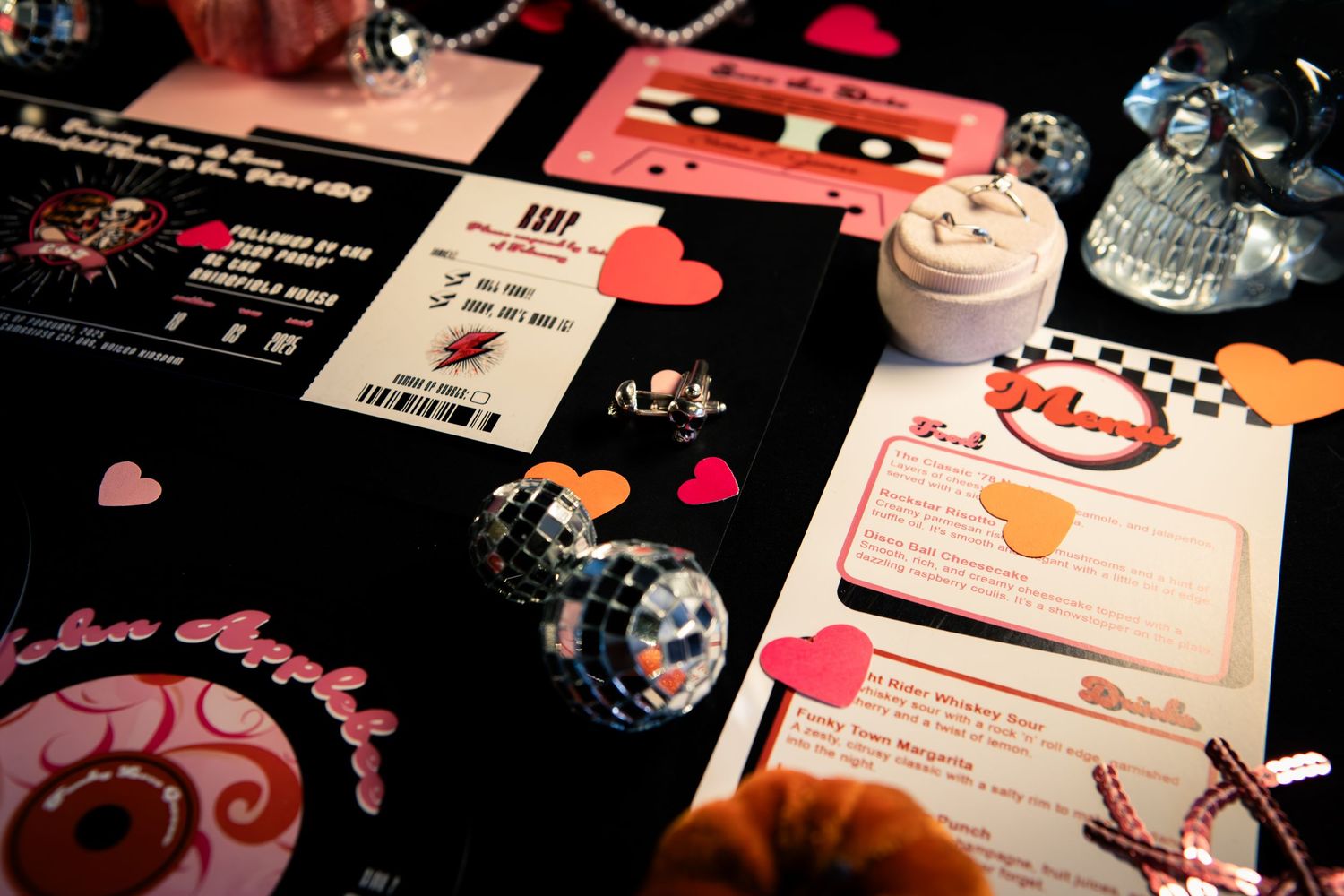 Wedding planning layout with red hearts, invitation cards and decorative elements on dark surface.