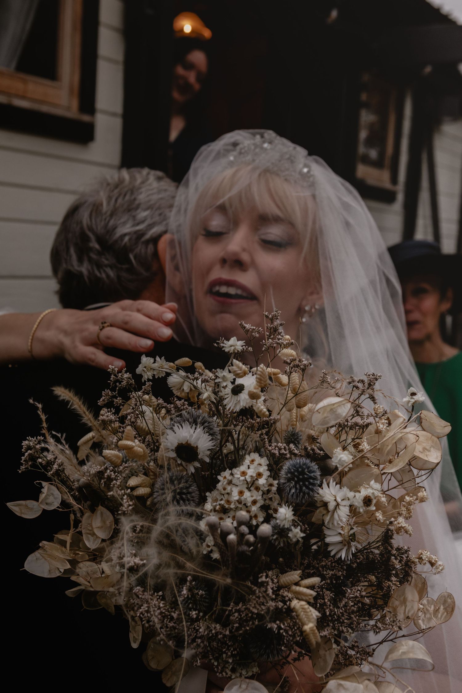 A close up photo of a bride holding a dried floral and sunflower wedding bouquet.