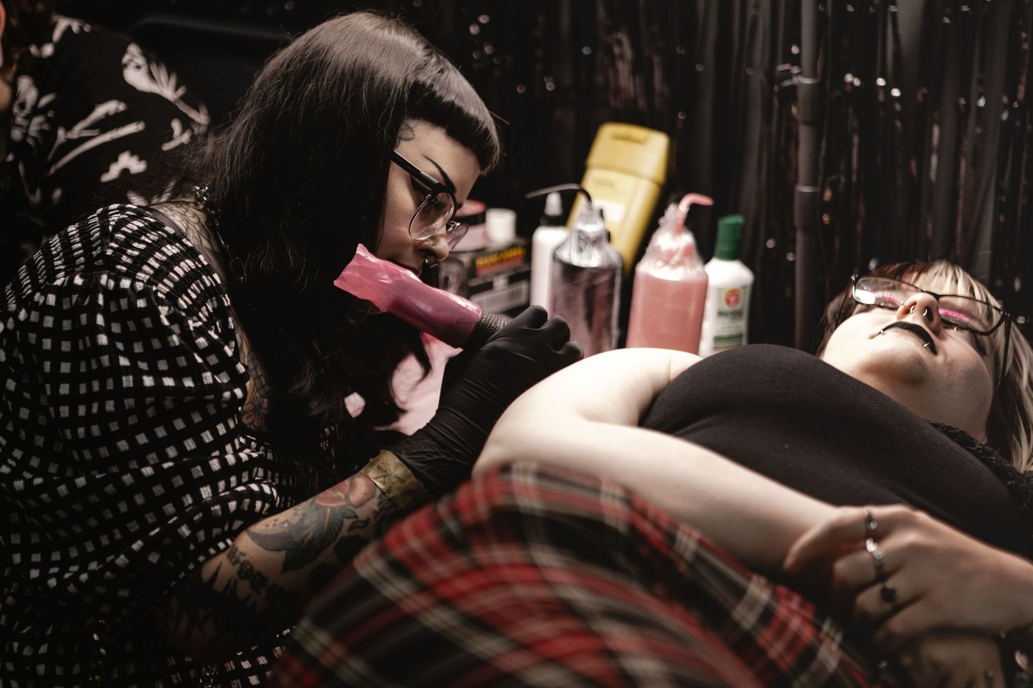 A dramatic series of black and white photographs showing professional tattooing in progress at a studio.
