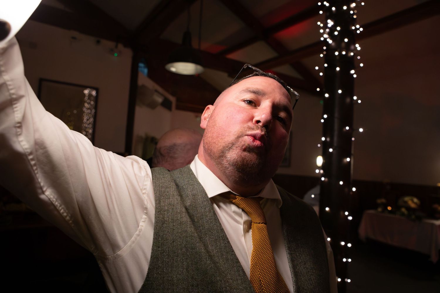 Celebration scene in pub with decorative lights and people raising drinks in toast.