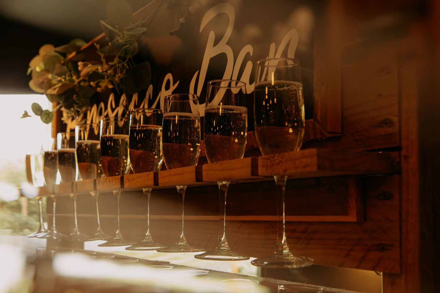 Romantic candles illuminate rustic wooden beams in a warm amber glow at an elegant wedding reception venue.
