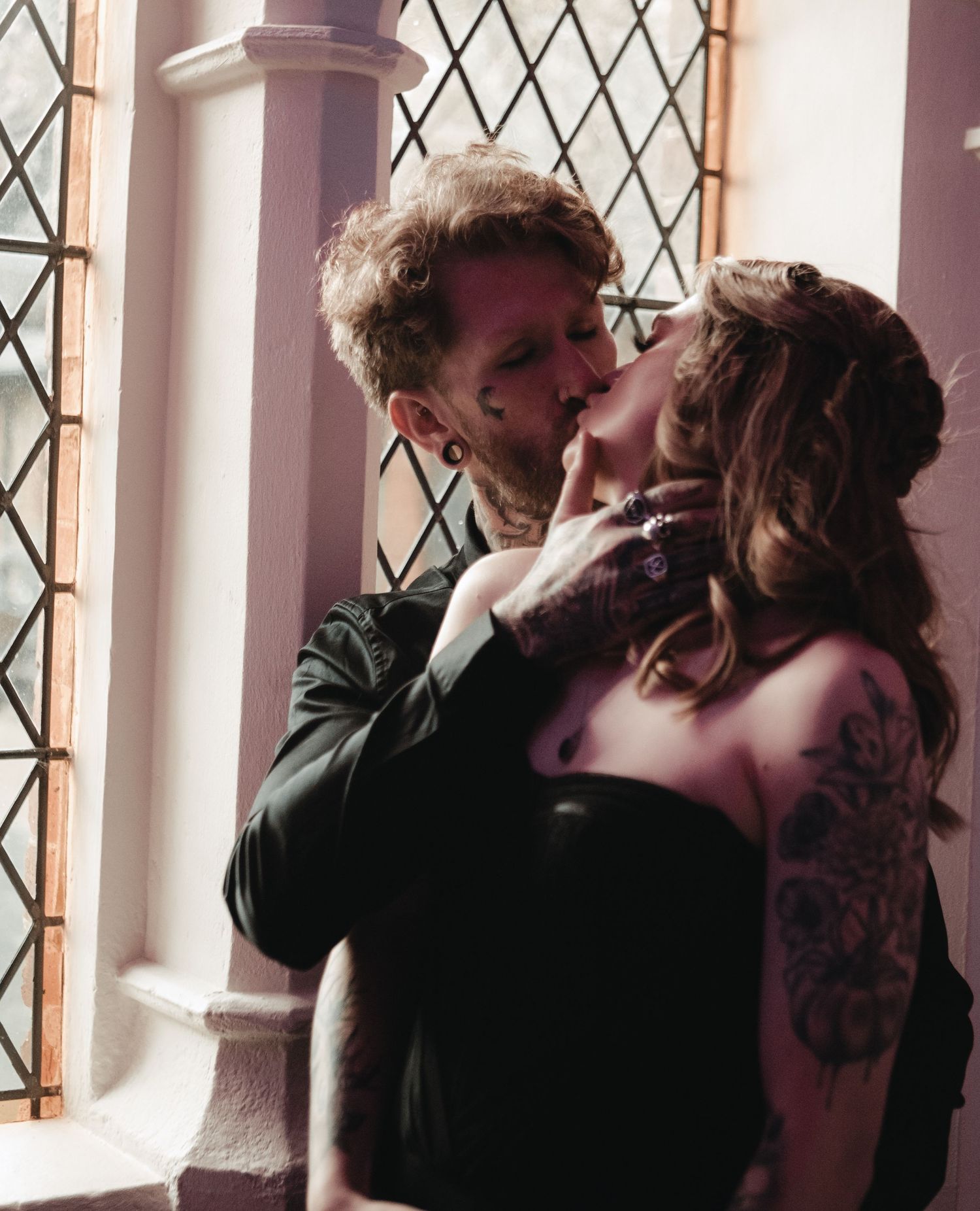 Silhouette of a romantic couple sharing an intimate moment by a window with diamond-patterned glass.