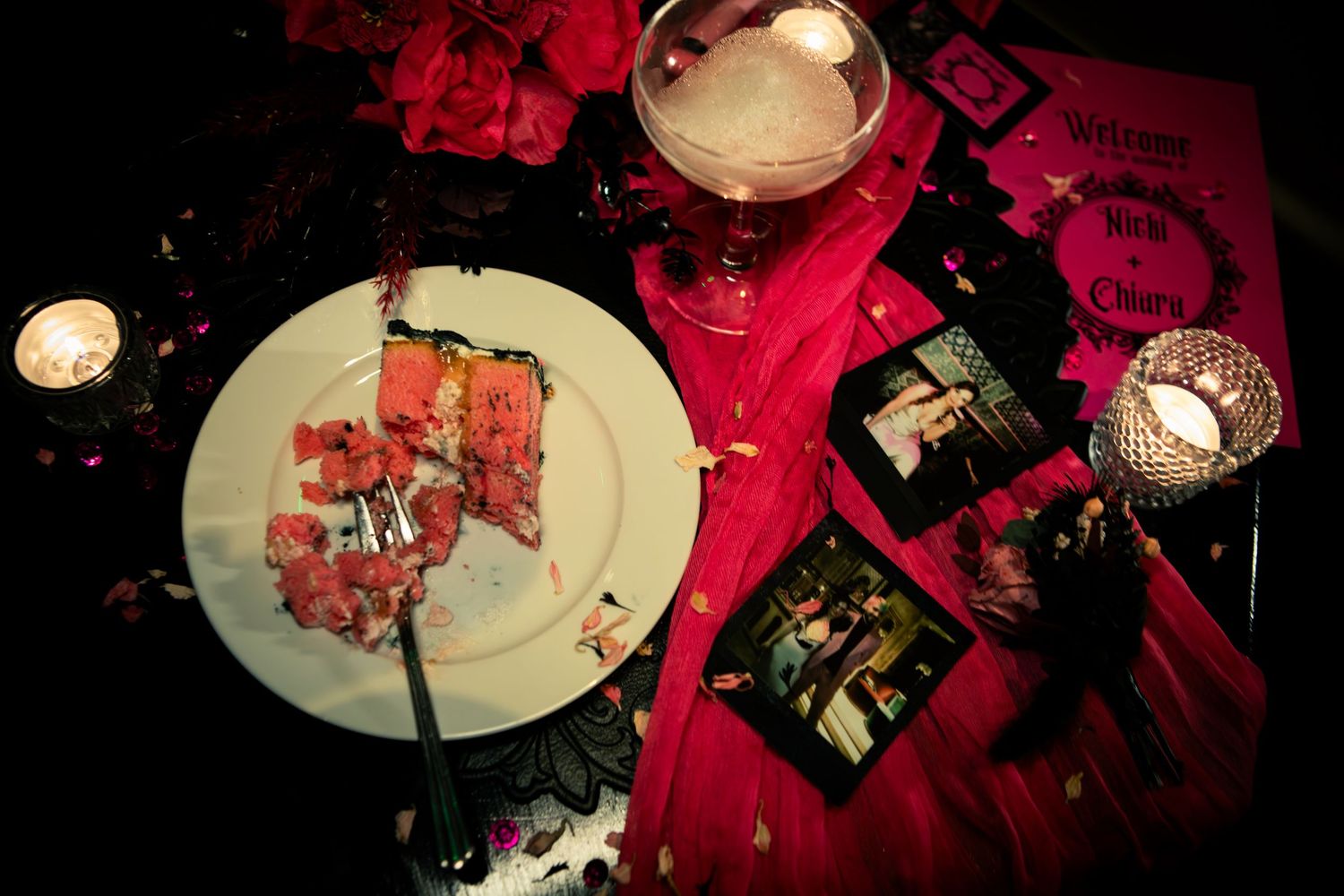 A half-eaten plate of food sits on a table with red decor and candlelight at a reception.