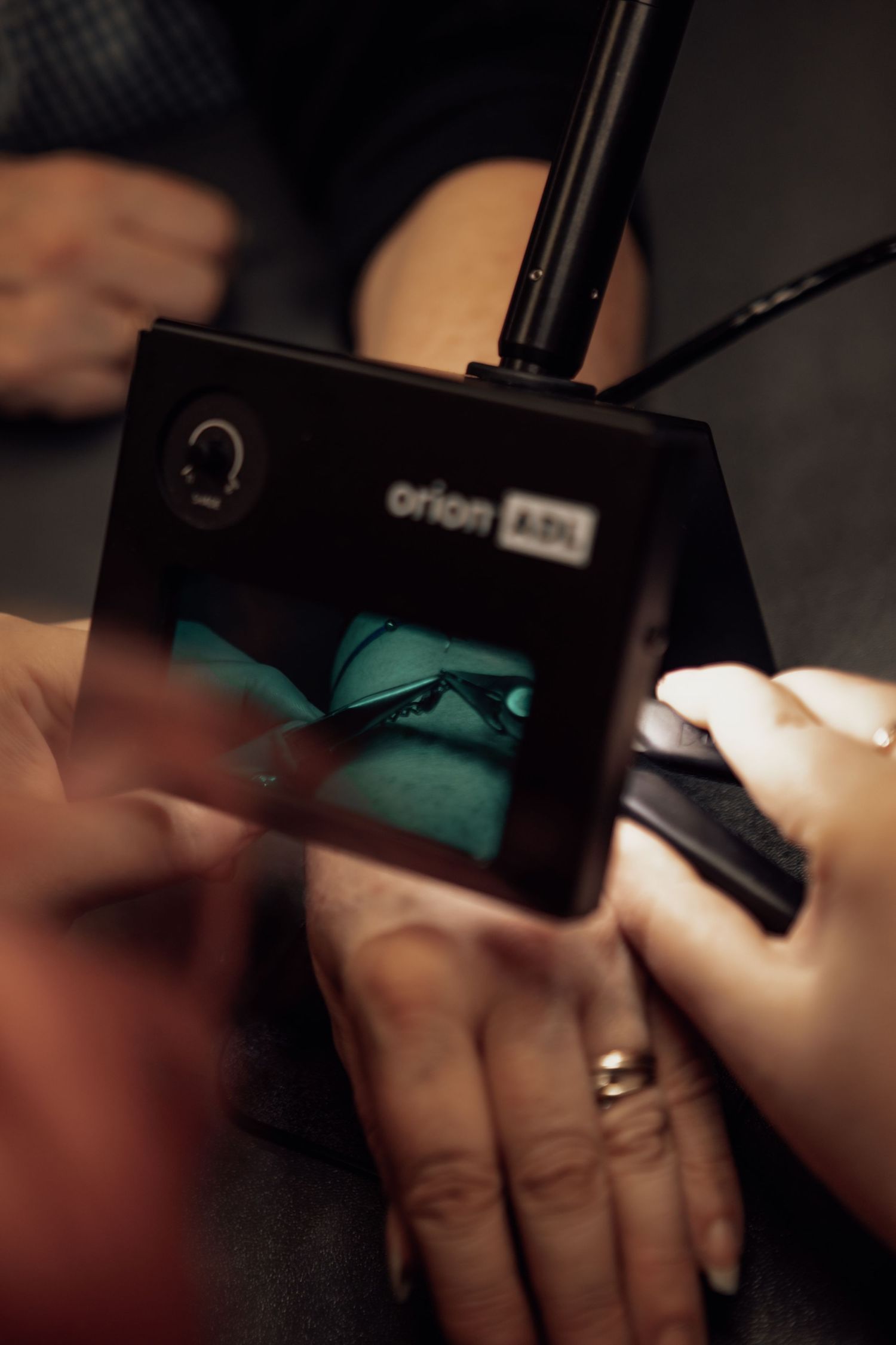 Hands apply nail polish in a series of steps showing the manicure process in dark lighting.