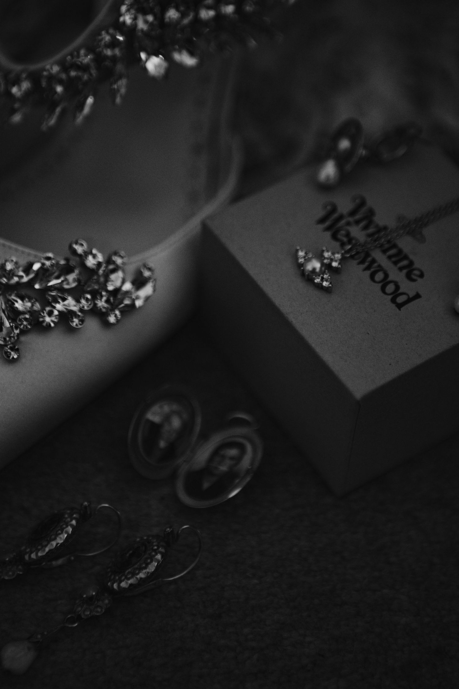A dark and moody wedding invitation with scattered diamonds and metal rings against a black background.