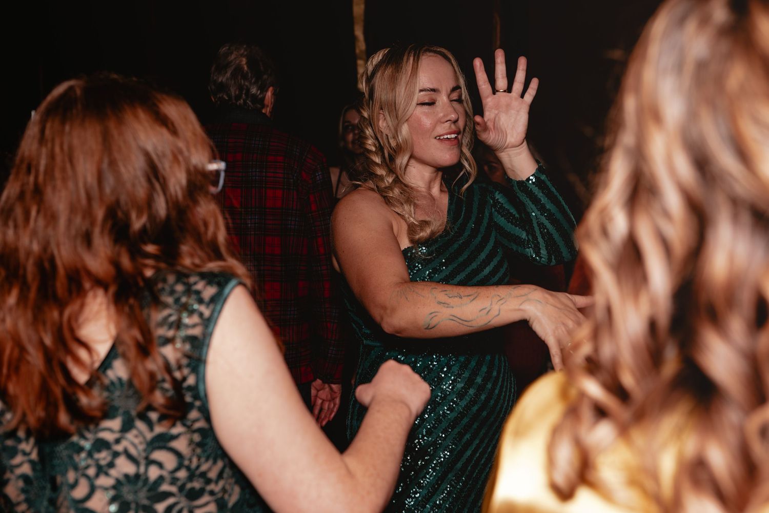 Women dancing and having fun at a celebration in dark emerald green attire.