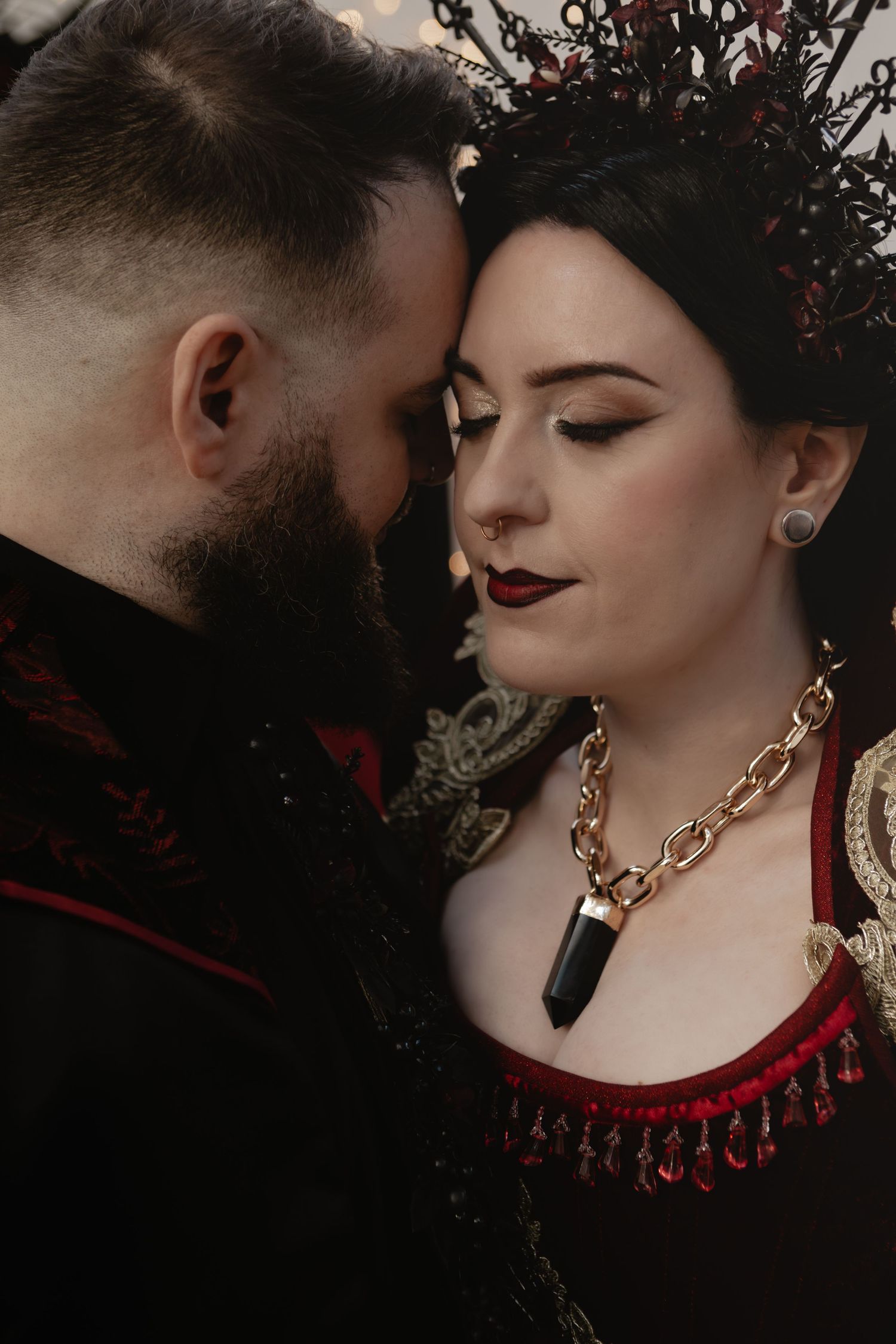 Dark romantic images show couple in intimate poses with gothic aesthetic featuring bold red and black colors and gold jewelry.
