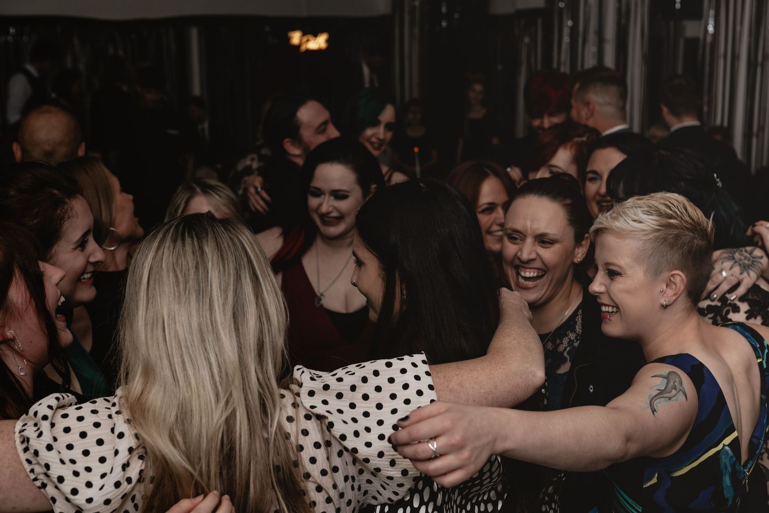 A crowded nightclub scene with people dancing and socializing in a dimly lit space.