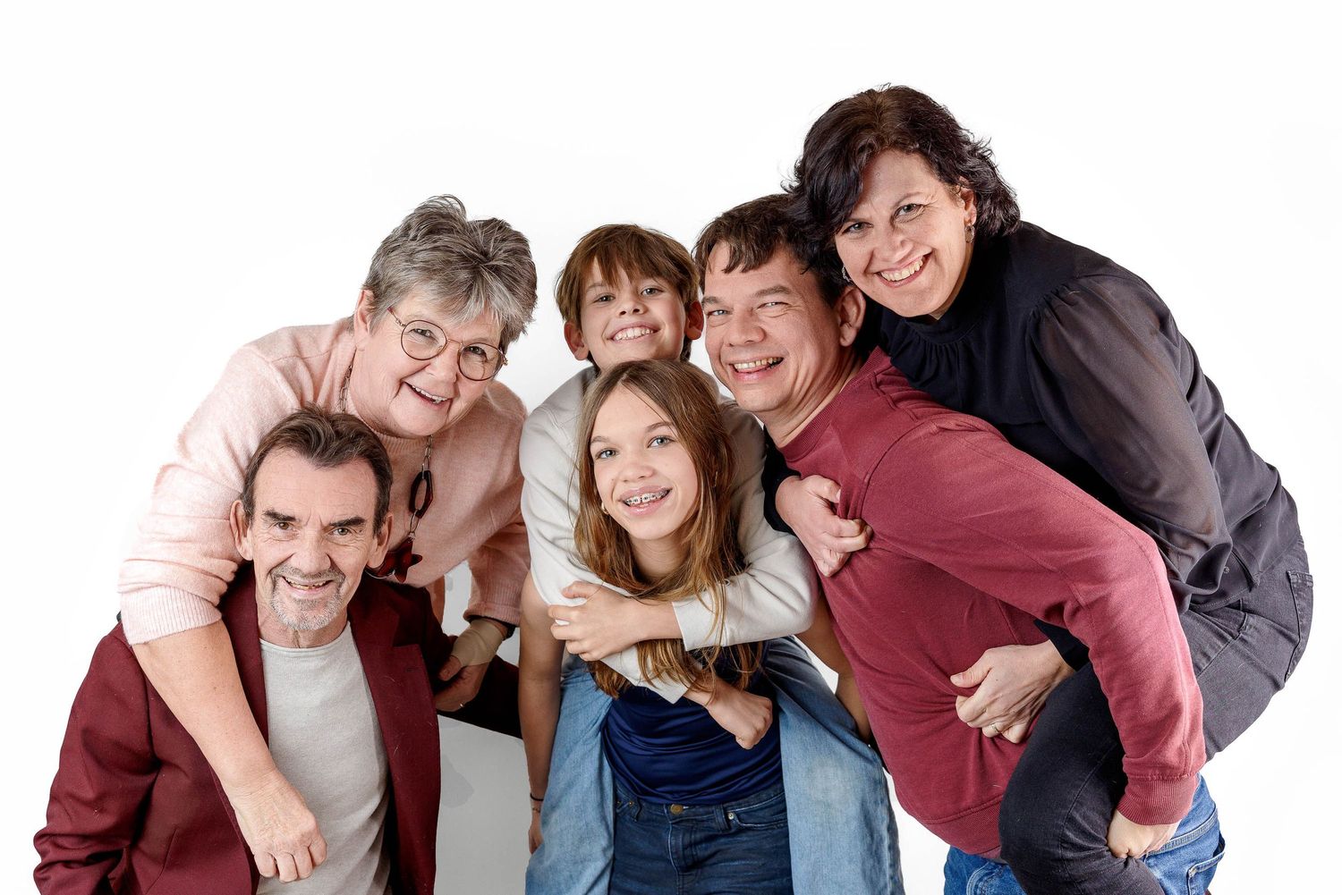 Group of happy people huddle together and smile while posing against a white background.