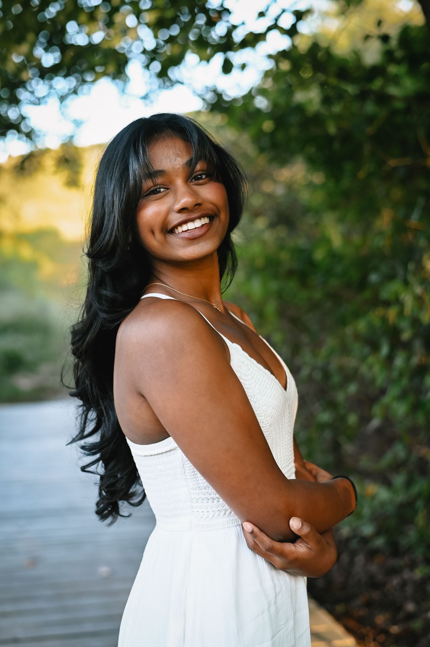 Massachusetts senior portraits featuring young woman wearing a white summer dress smiling joyfully