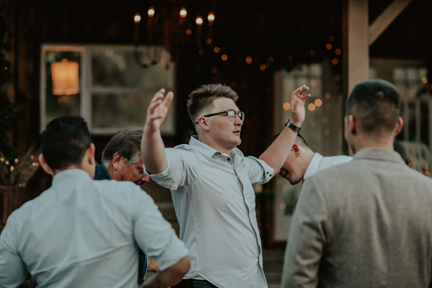 People celebrating at an outdoor event with string lights hanging overhead in the evening.