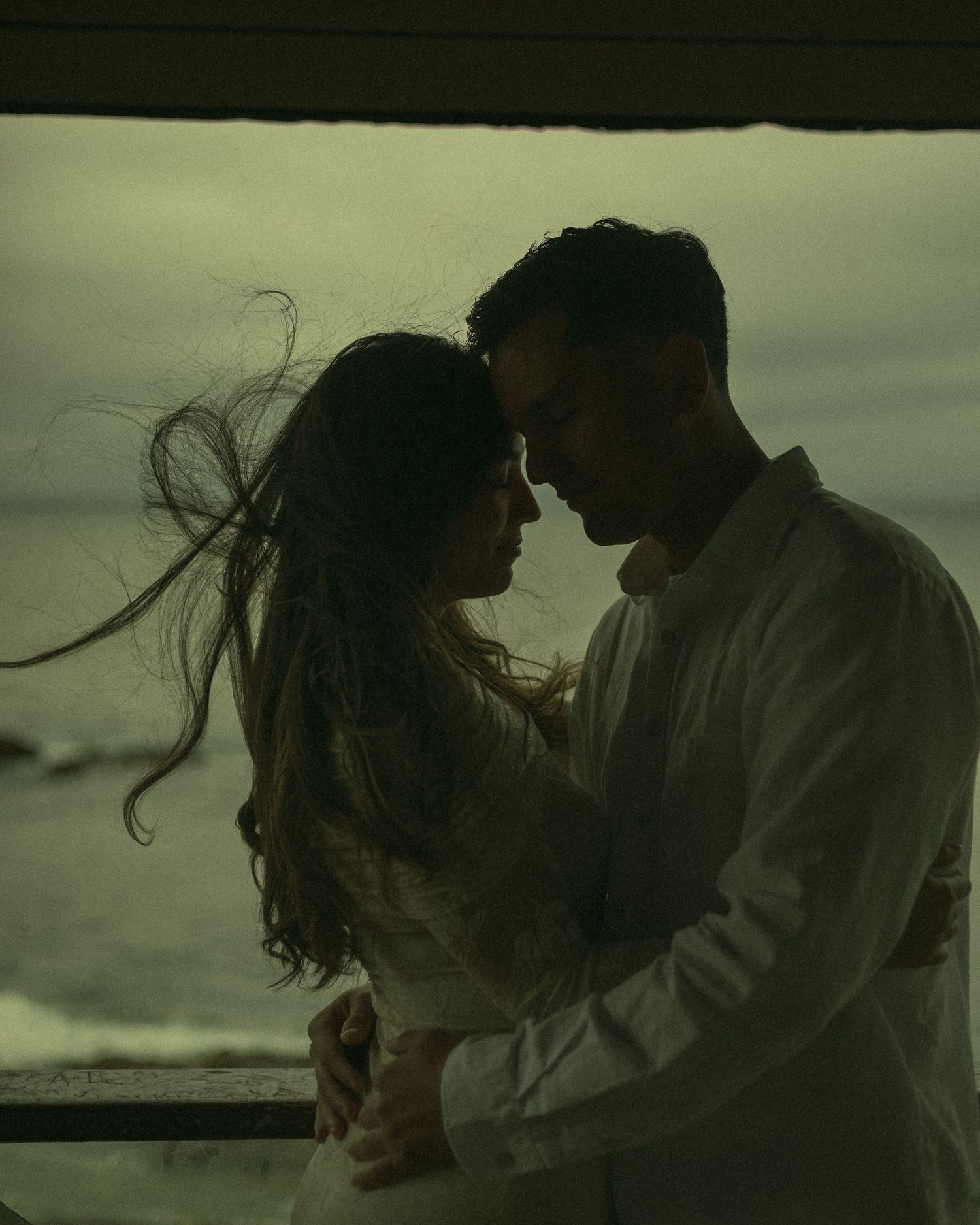 Couple sharing an intimate moment on a windy rainy day at Laguna Beach, California.