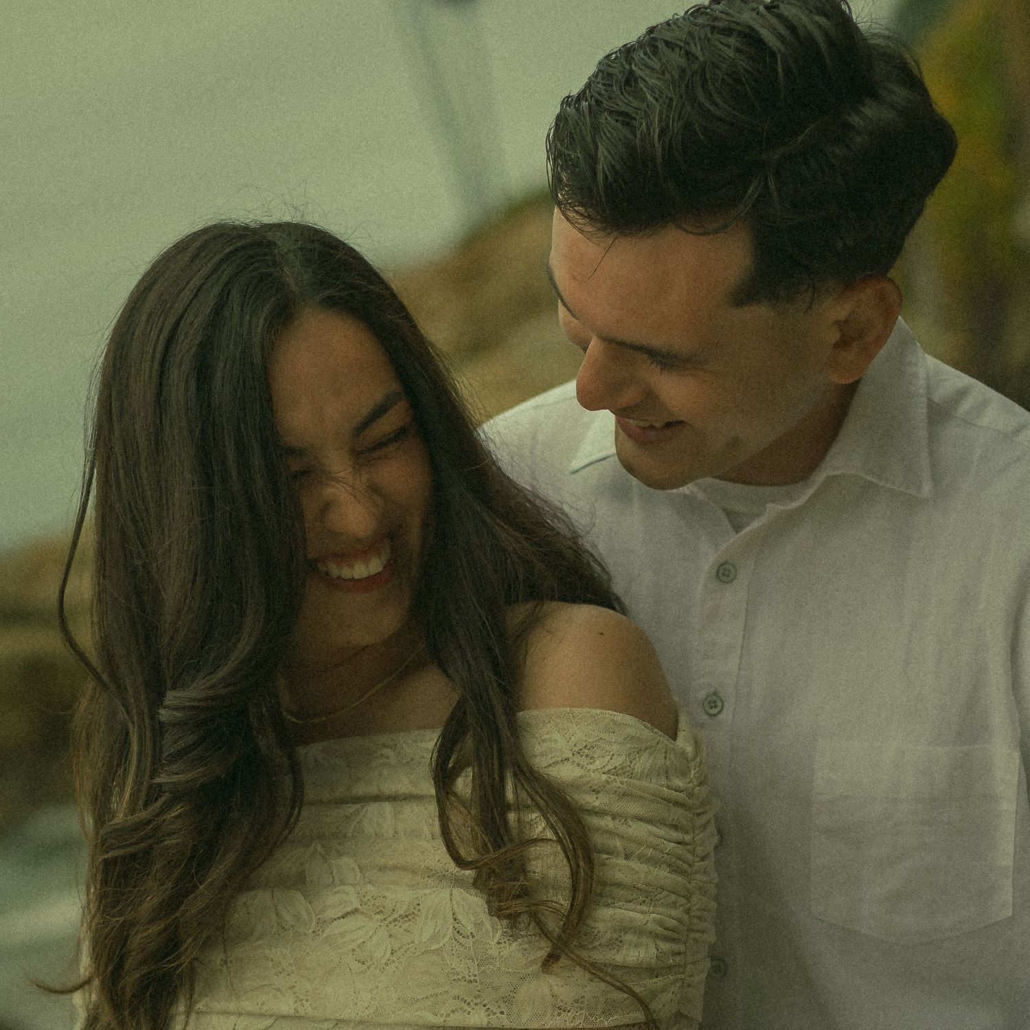 Couple laughing together while in a warm embrace on a cold beach day.