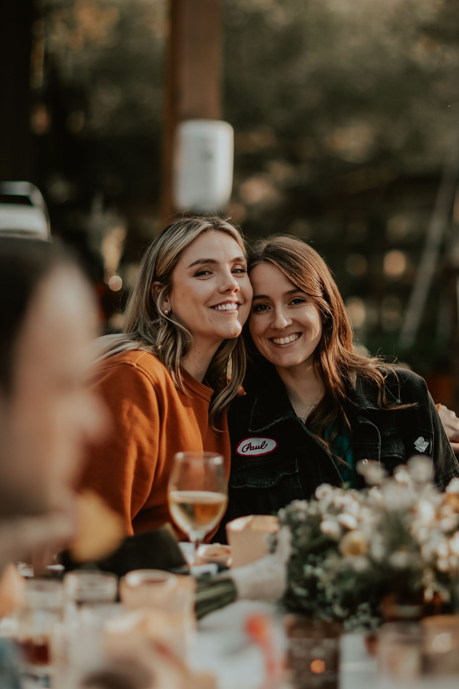 Two friends share a candid moment at an outdoor wedding venue in Southern California