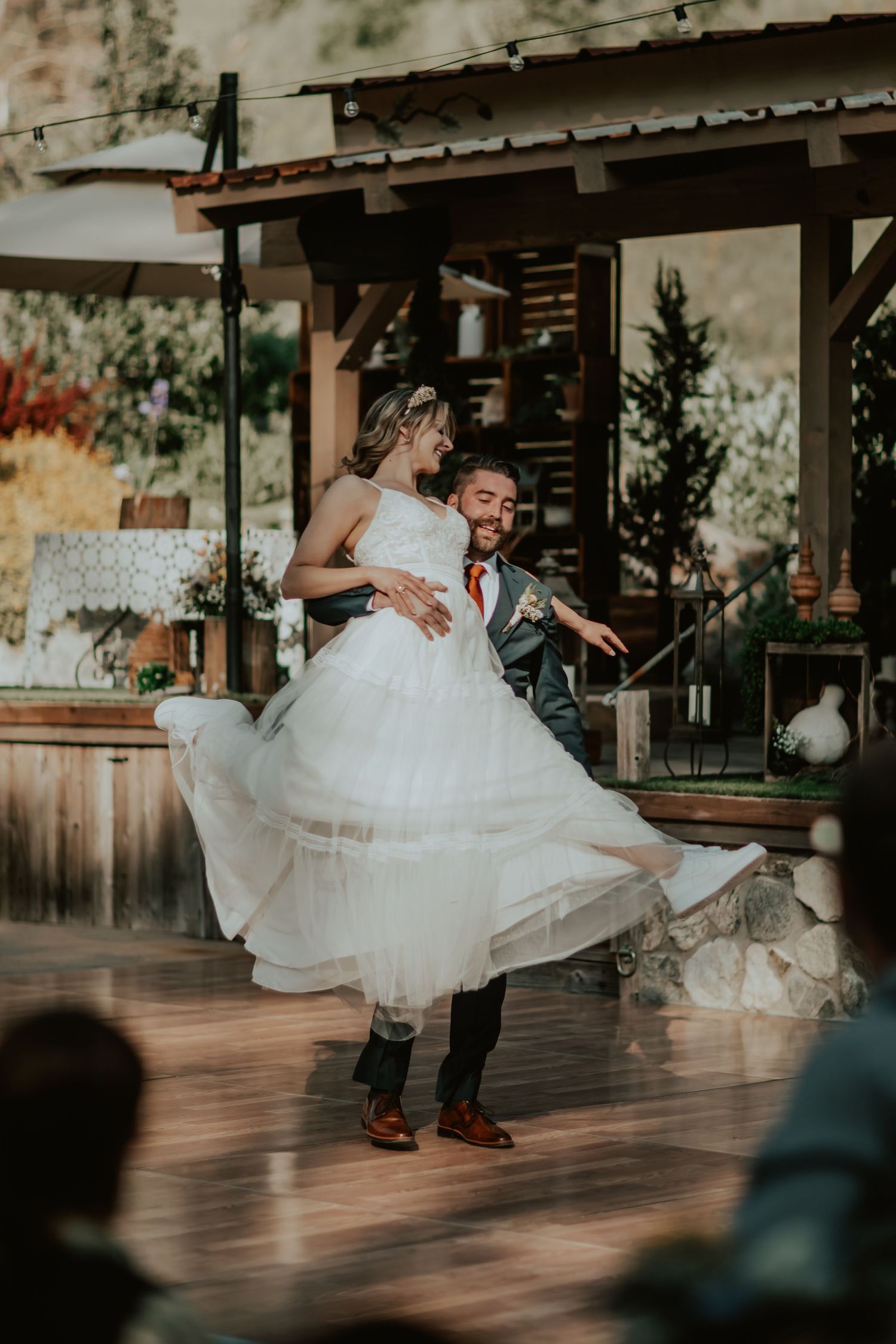 A couple shares their first dance at an outdoor wedding reception, with the bride's white tulle dress flowing in motion.