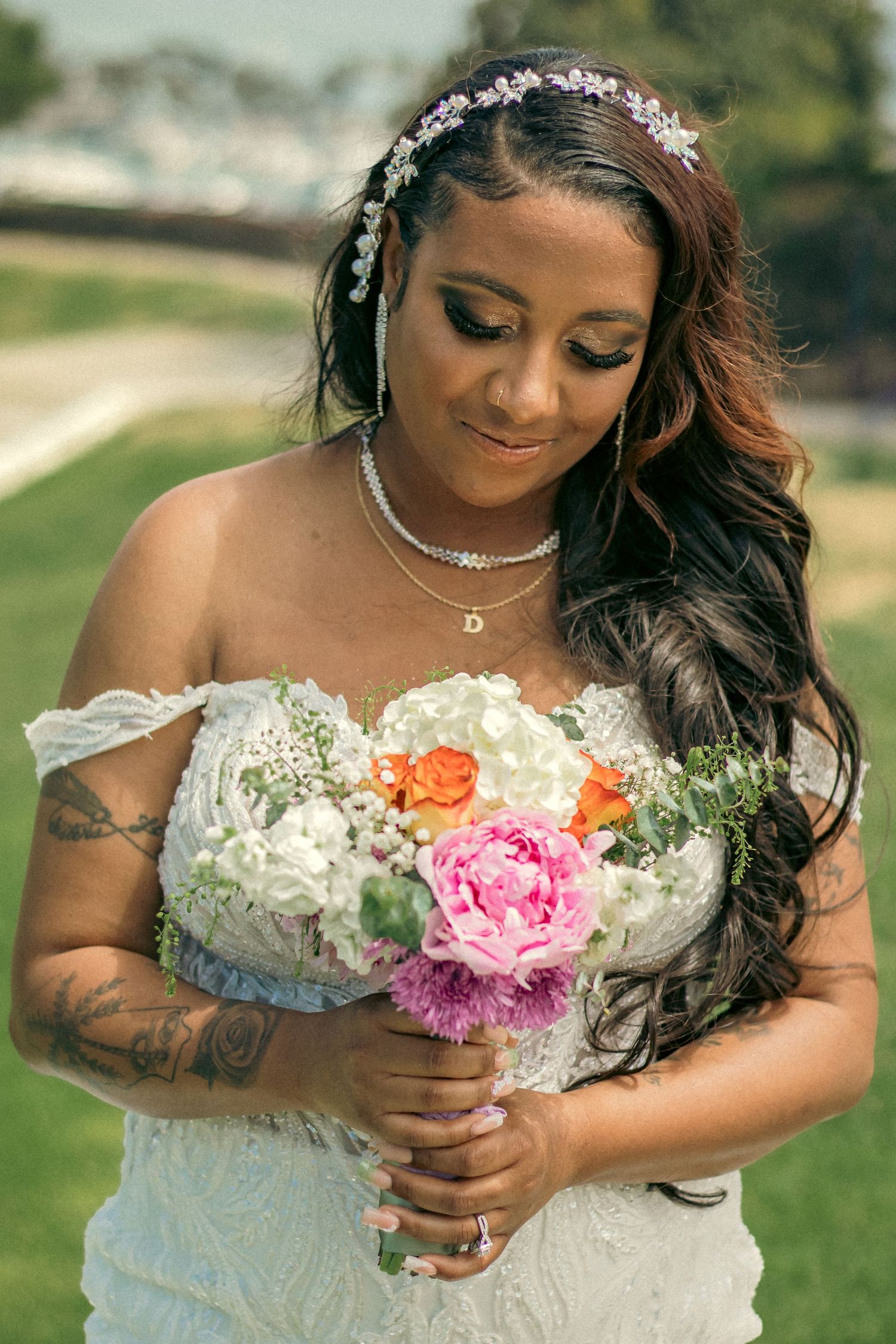 A bride in a white strapless gown holds a colorful bouquet featuring pink and orange flowers with crystal hair accessories in Dana Point