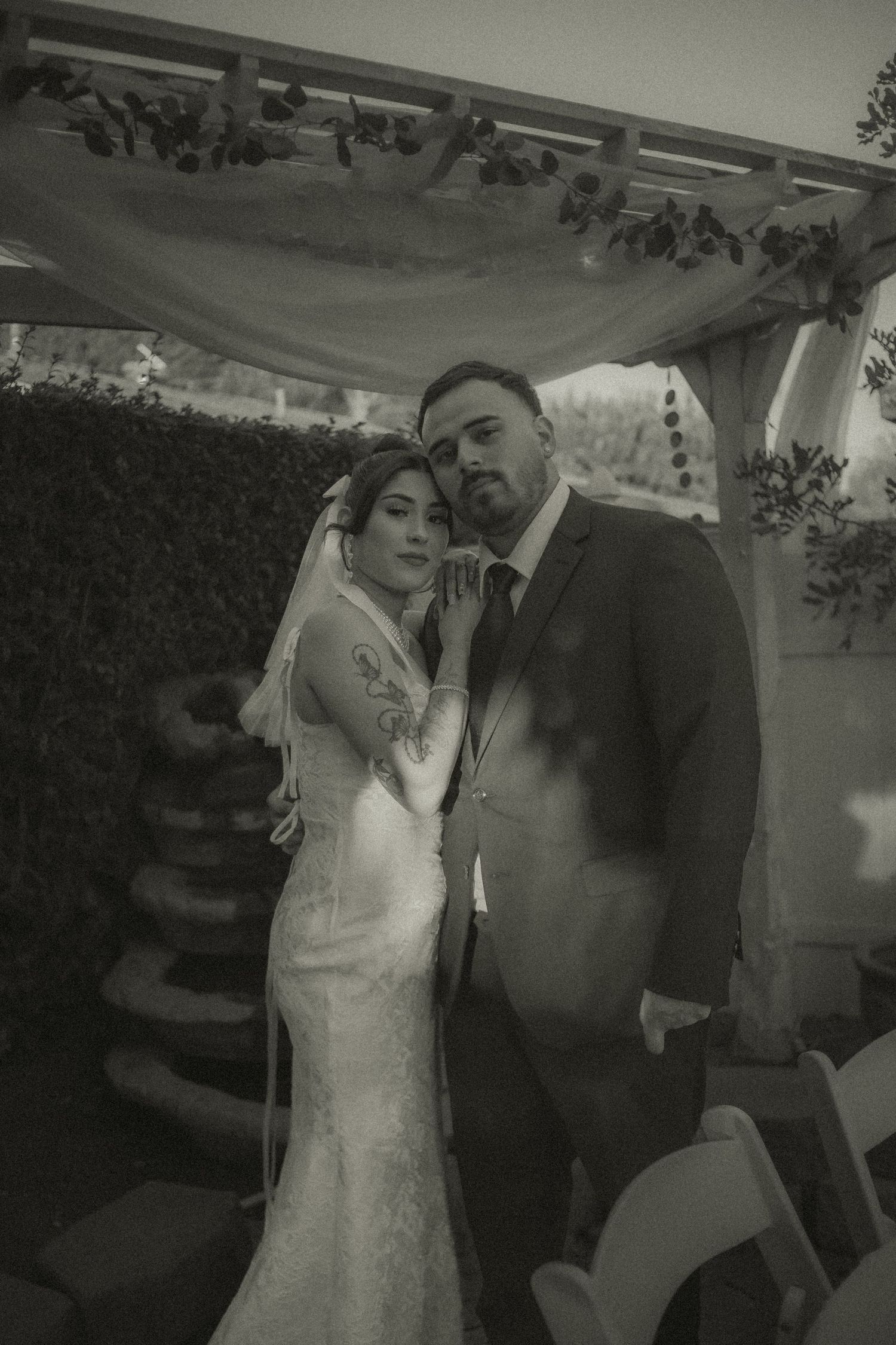 A romantic black and white wedding photo showing a couple in an intimate pose under the alter