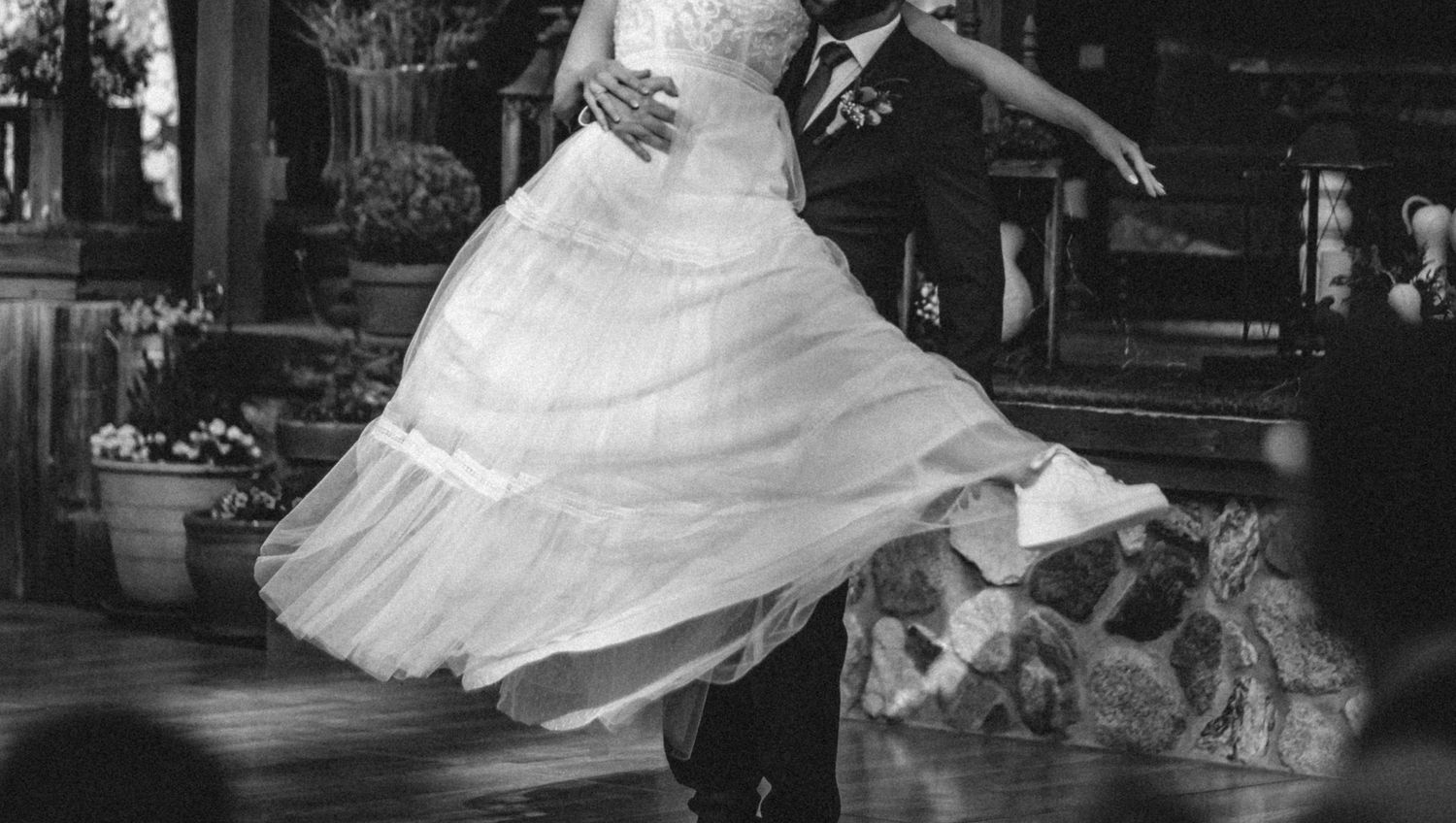 A couple dances together in a flowing white wedding gown and formal attire for their first dance as bride and groom